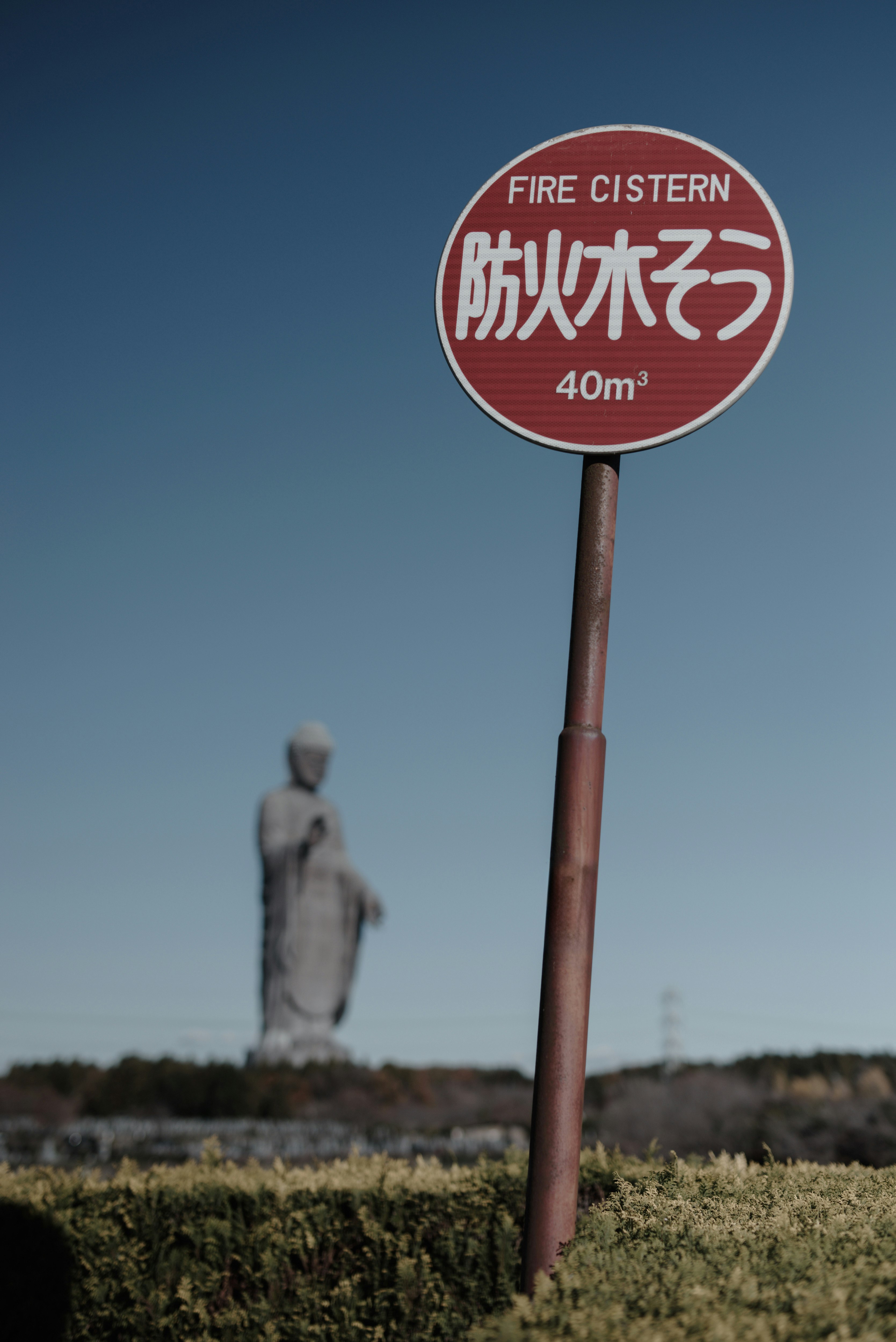 青空の下の防火水そう標識と牛久大仏