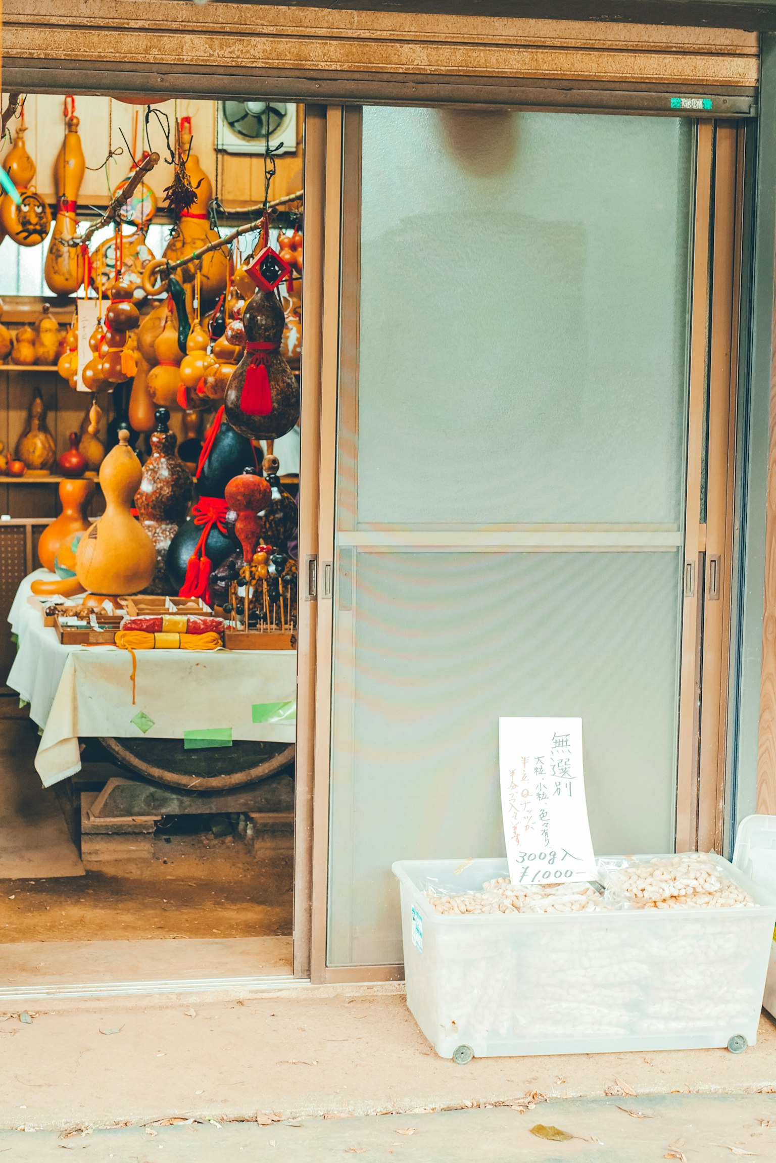 Ingresso di un piccolo negozio con porte in legno decorate con vari prodotti e artigianato