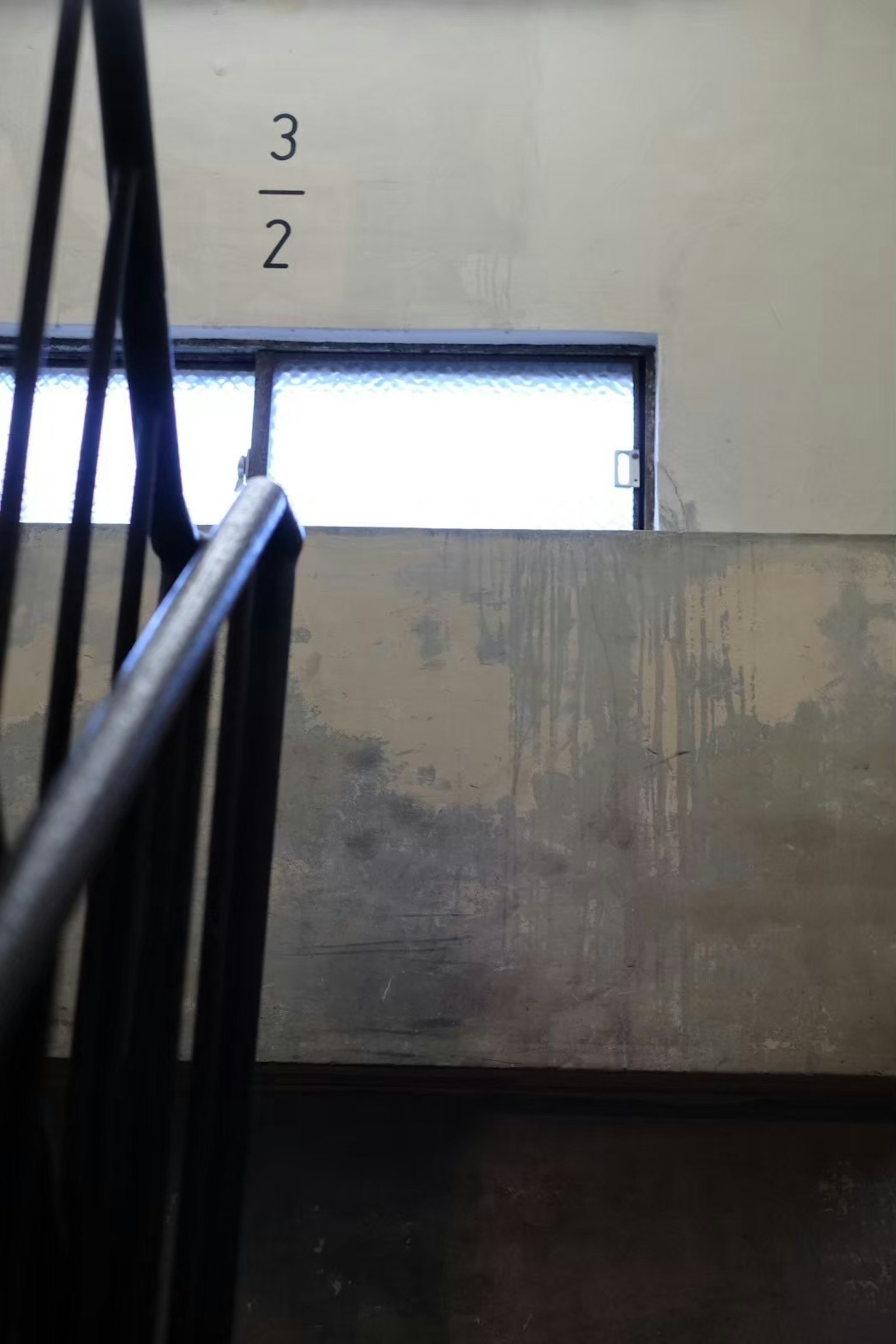 Staircase railing with concrete wall and window in a minimalist space