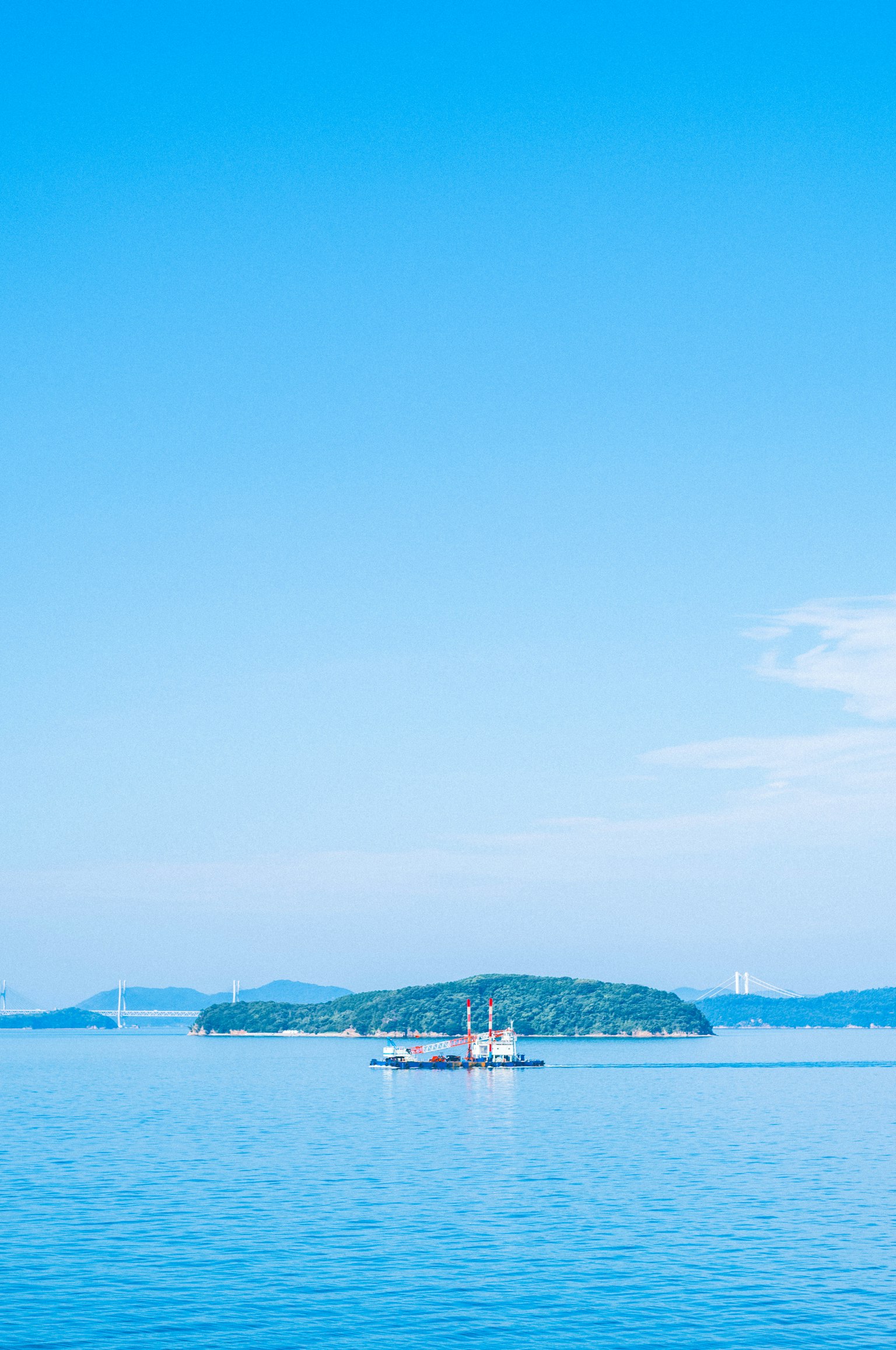 Piccola isola e barca su un mare blu calmo sotto un cielo sereno