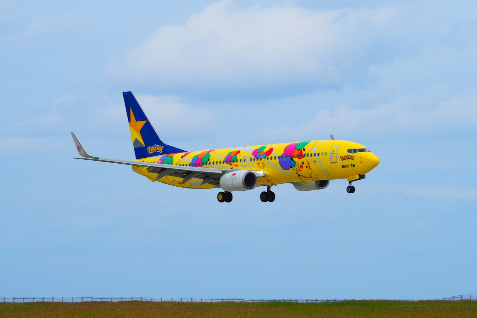 Bunt gestaltetes gelbes Flugzeug landet vor einem blauen Himmel