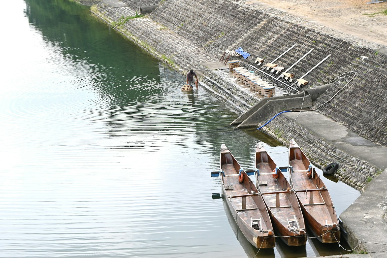 เรือไม้บนผิวน้ำสงบพร้อมคนยืนอยู่ที่ชายฝั่ง