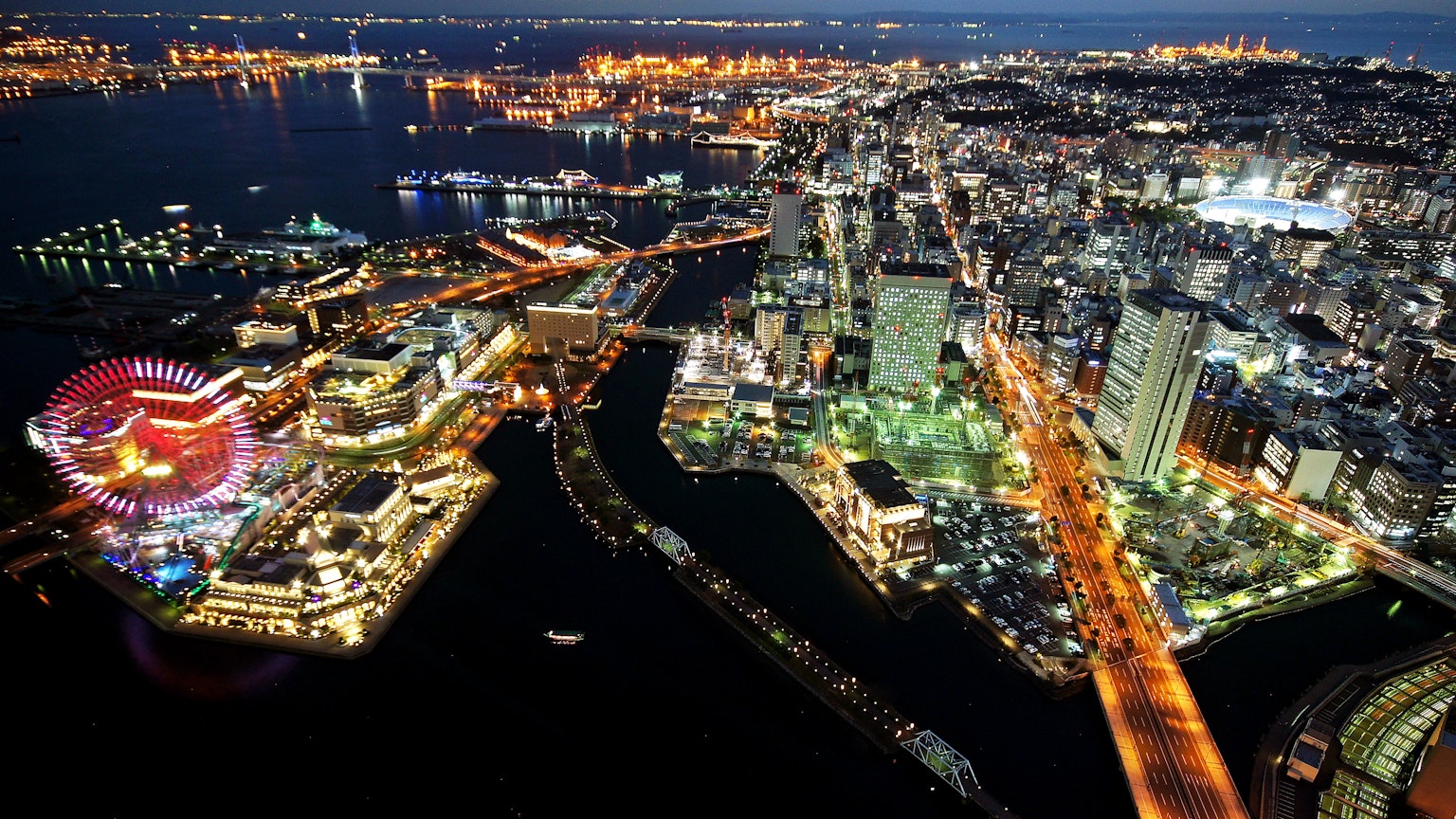 Panorama notturno con edifici illuminati e ruota panoramica colorata sul waterfront