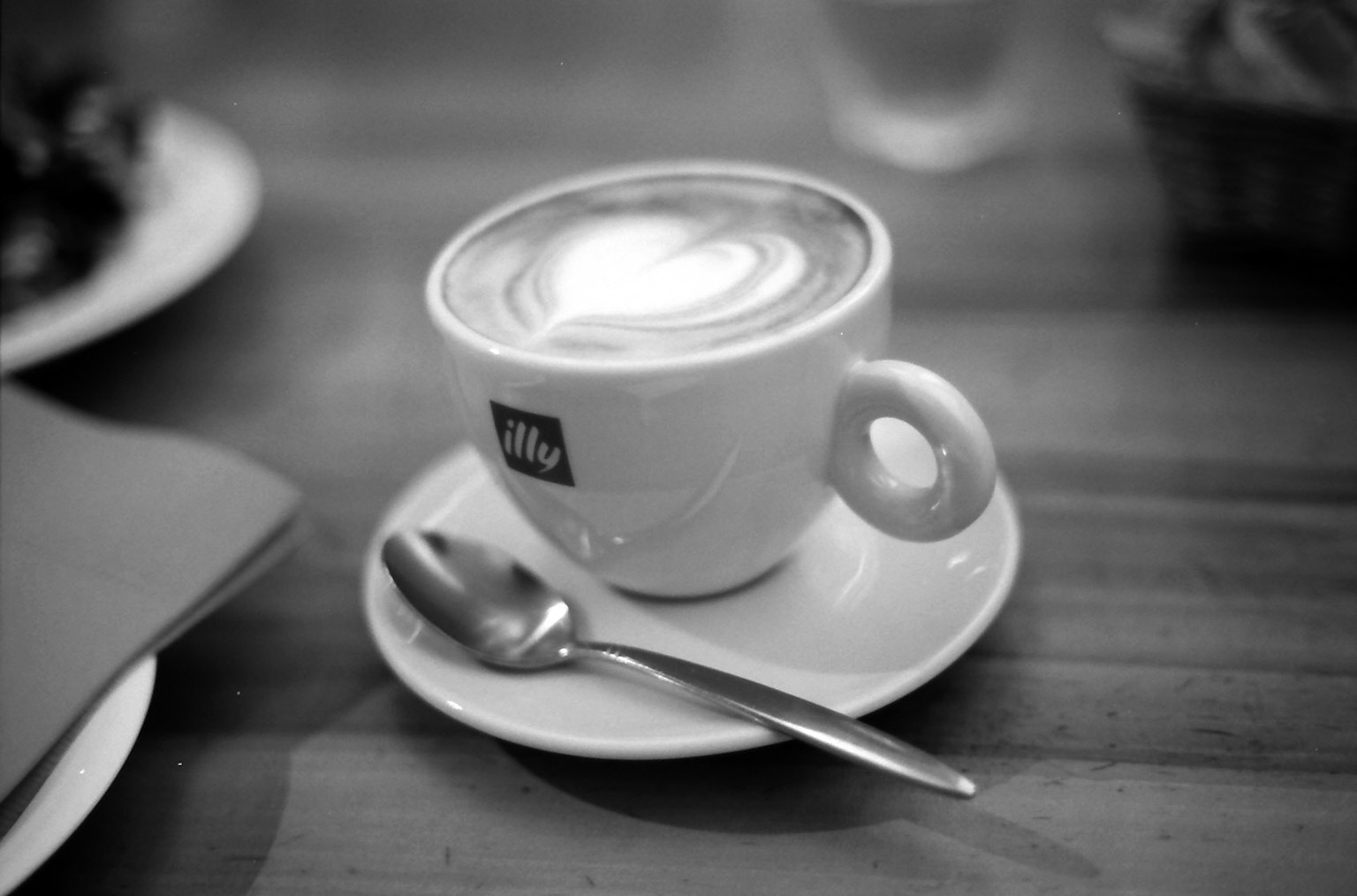 Hình ảnh đen trắng của latte với thiết kế hình trái tim trong cốc và đĩa