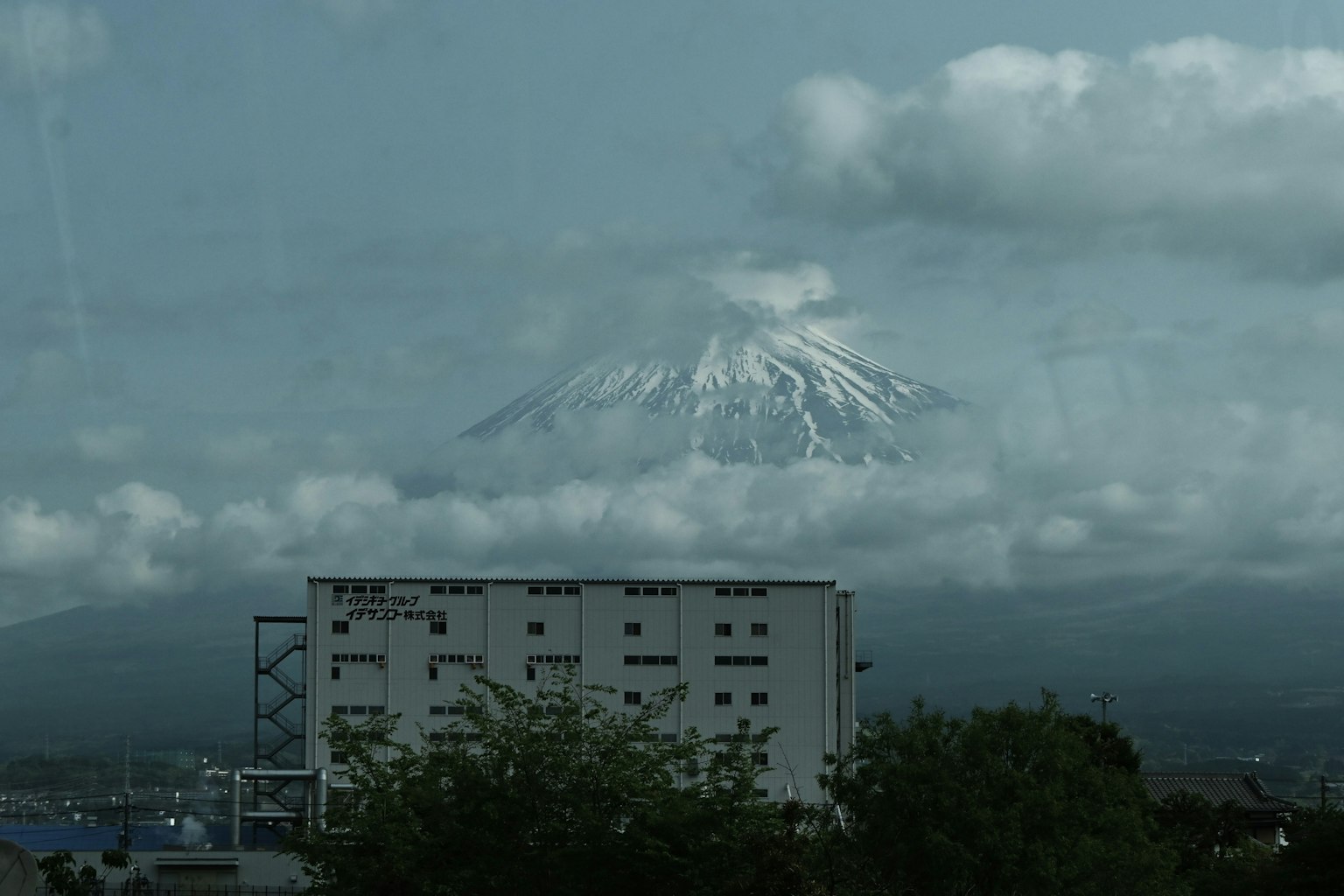 Vista del monte Fuji parcialmente cubierto por nubes con un edificio en primer plano