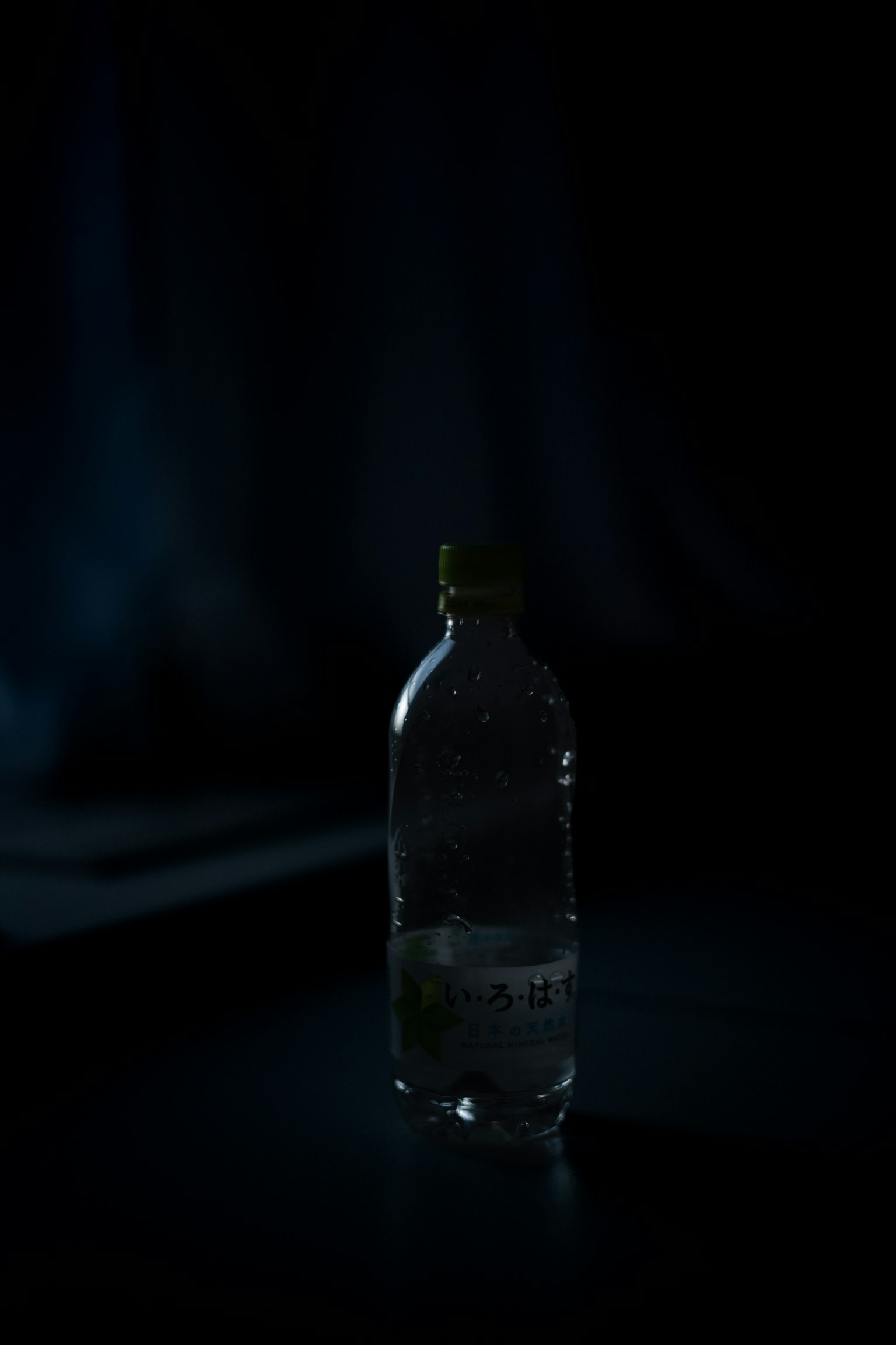 Una botella de agua iluminada contra un fondo oscuro