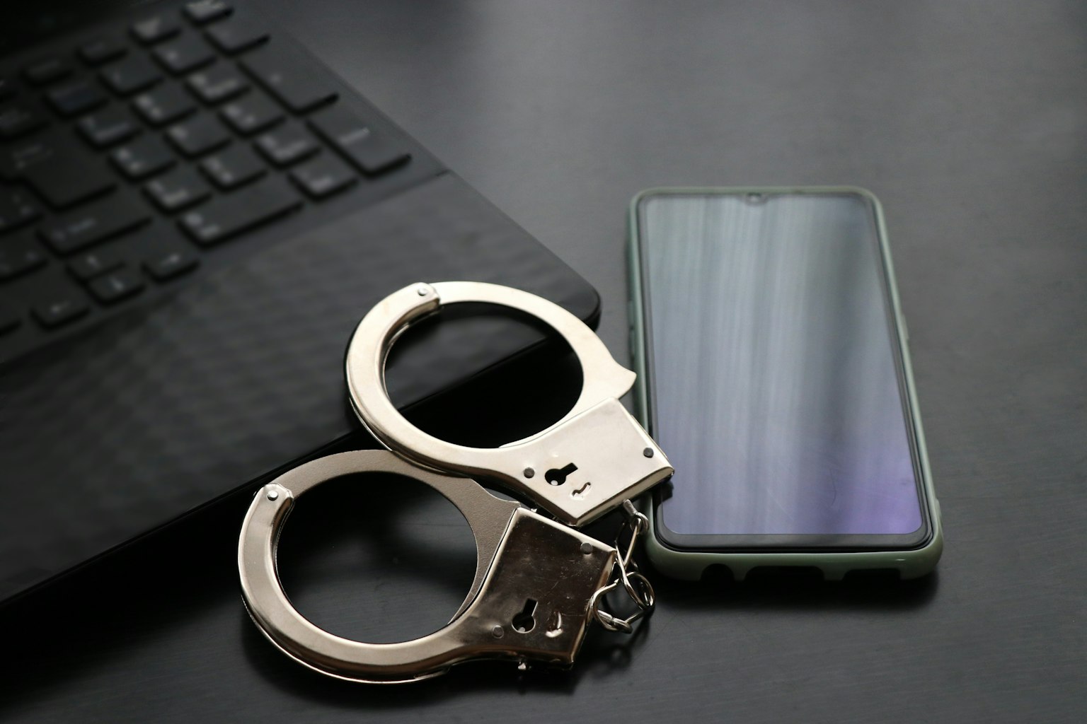 Handcuff dan smartphone di atas permukaan hitam