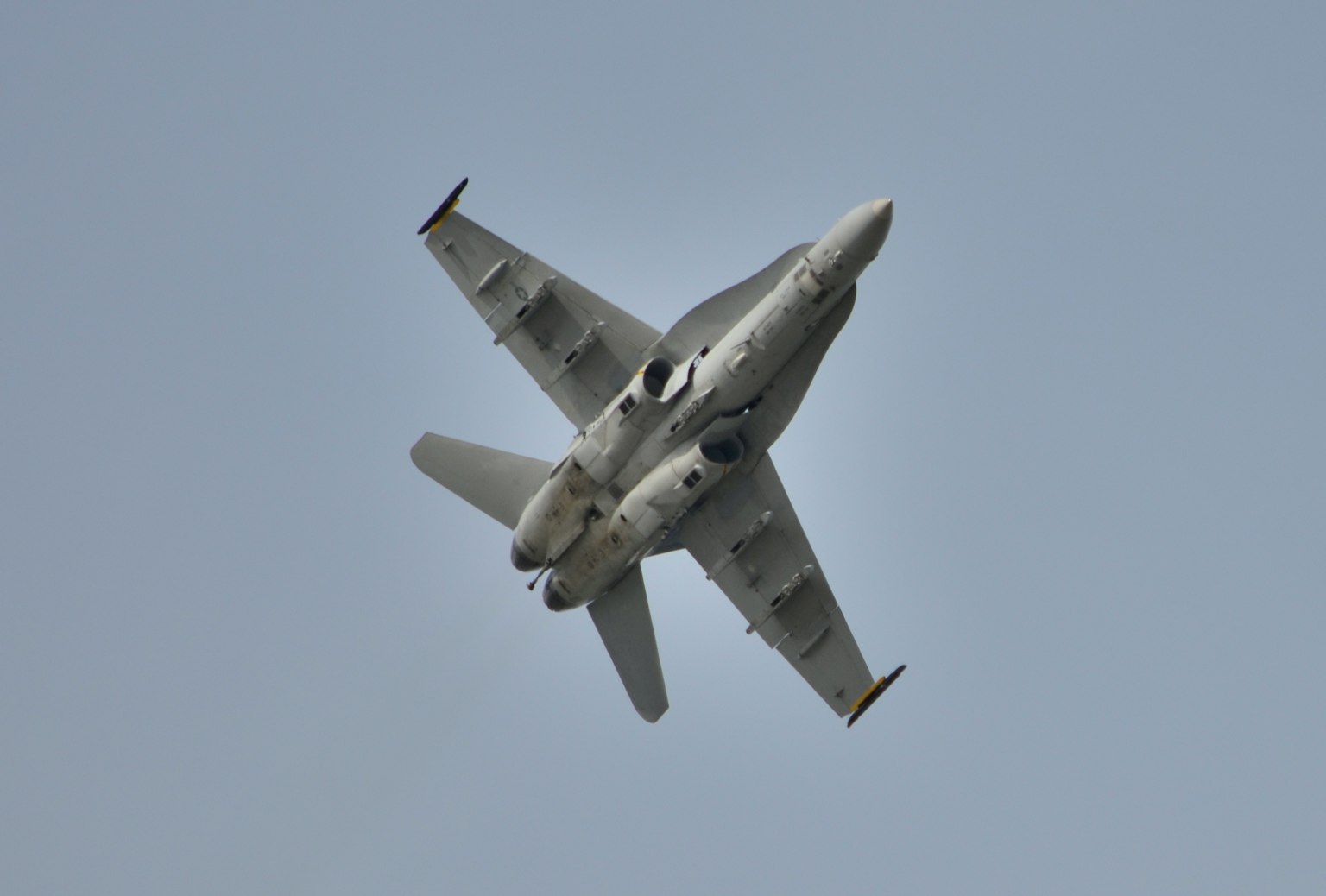 Top view of a fighter jet in flight against a blue sky