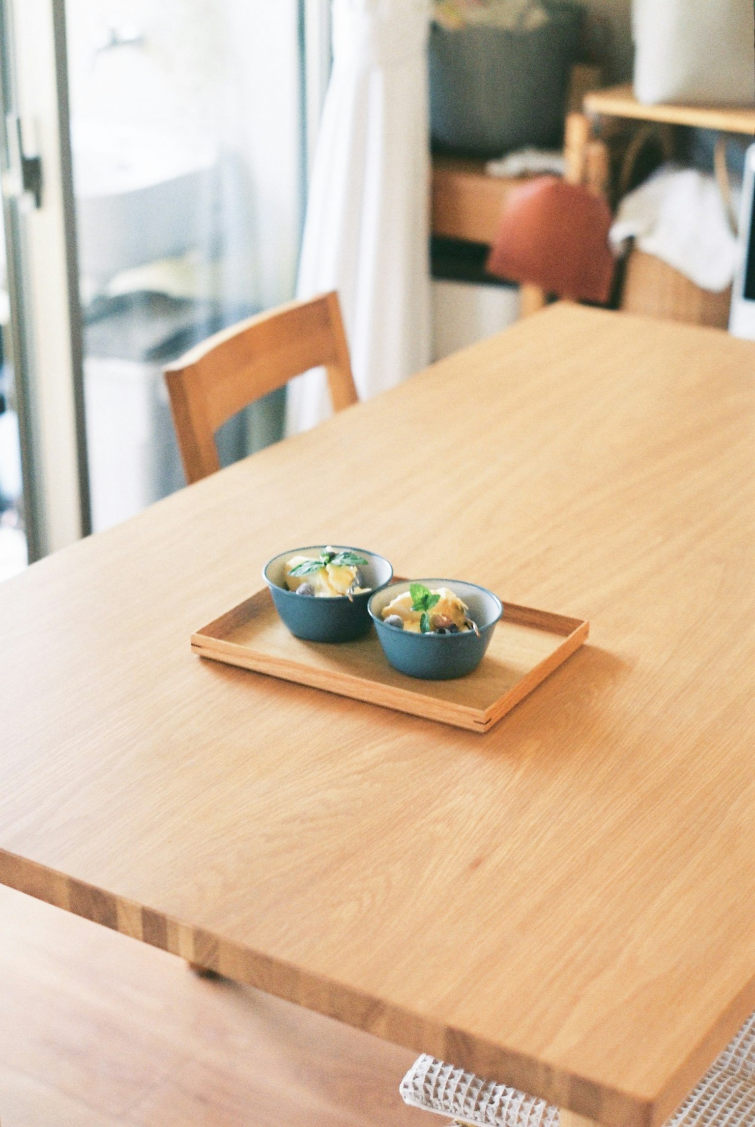Tavolo da pranzo semplice con superficie in legno che presenta due ciotole blu di cibo su un vassoio di legno
