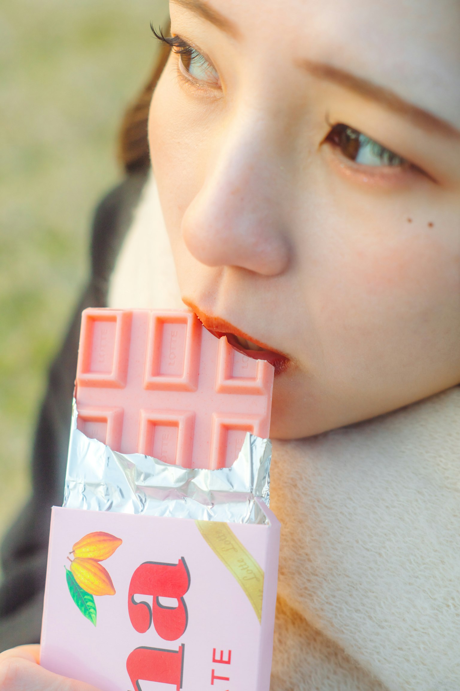 A woman about to bite into a pink chocolate bar
