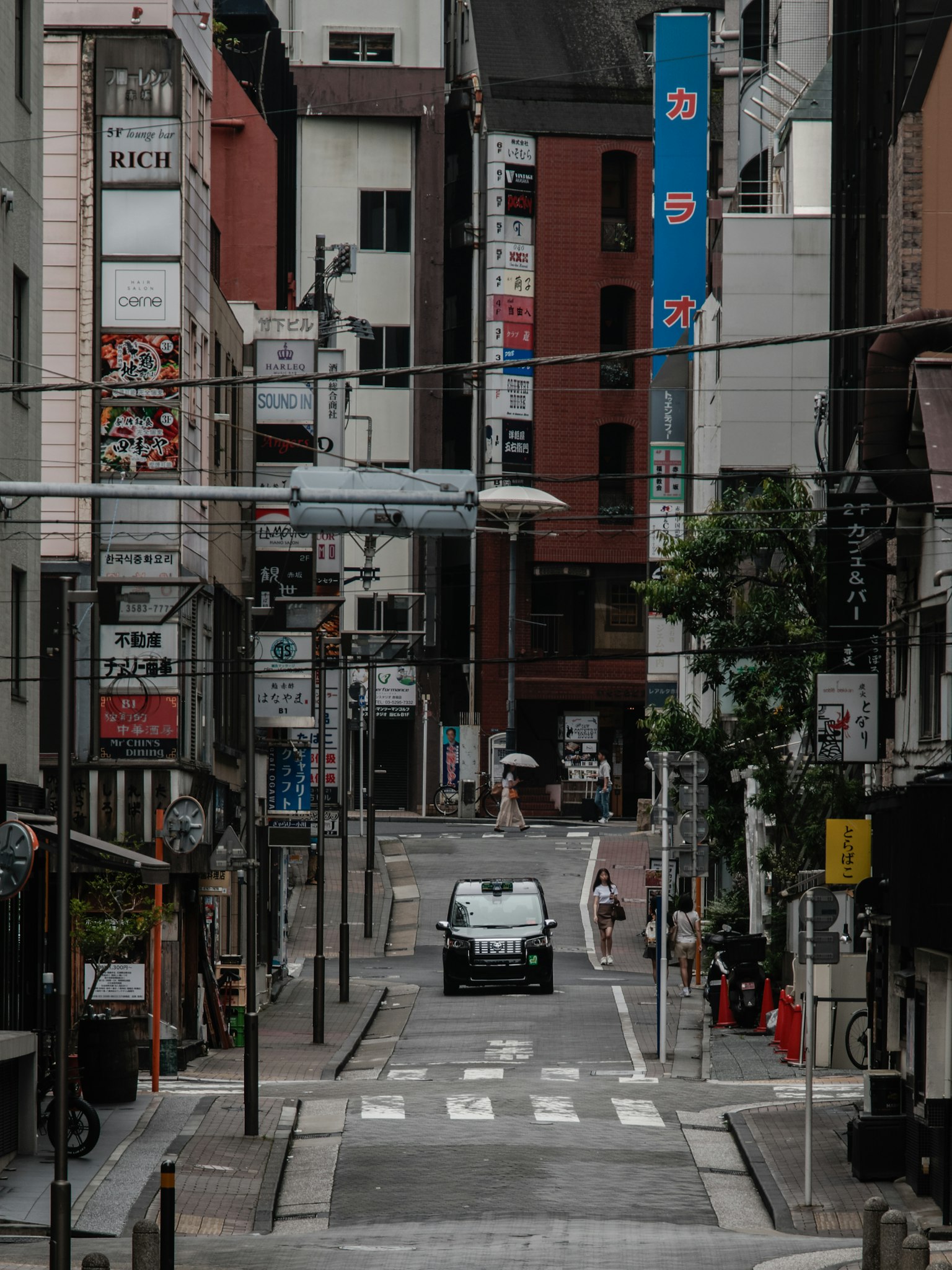 Una macchina che percorre una strada stretta con edifici antichi e insegne