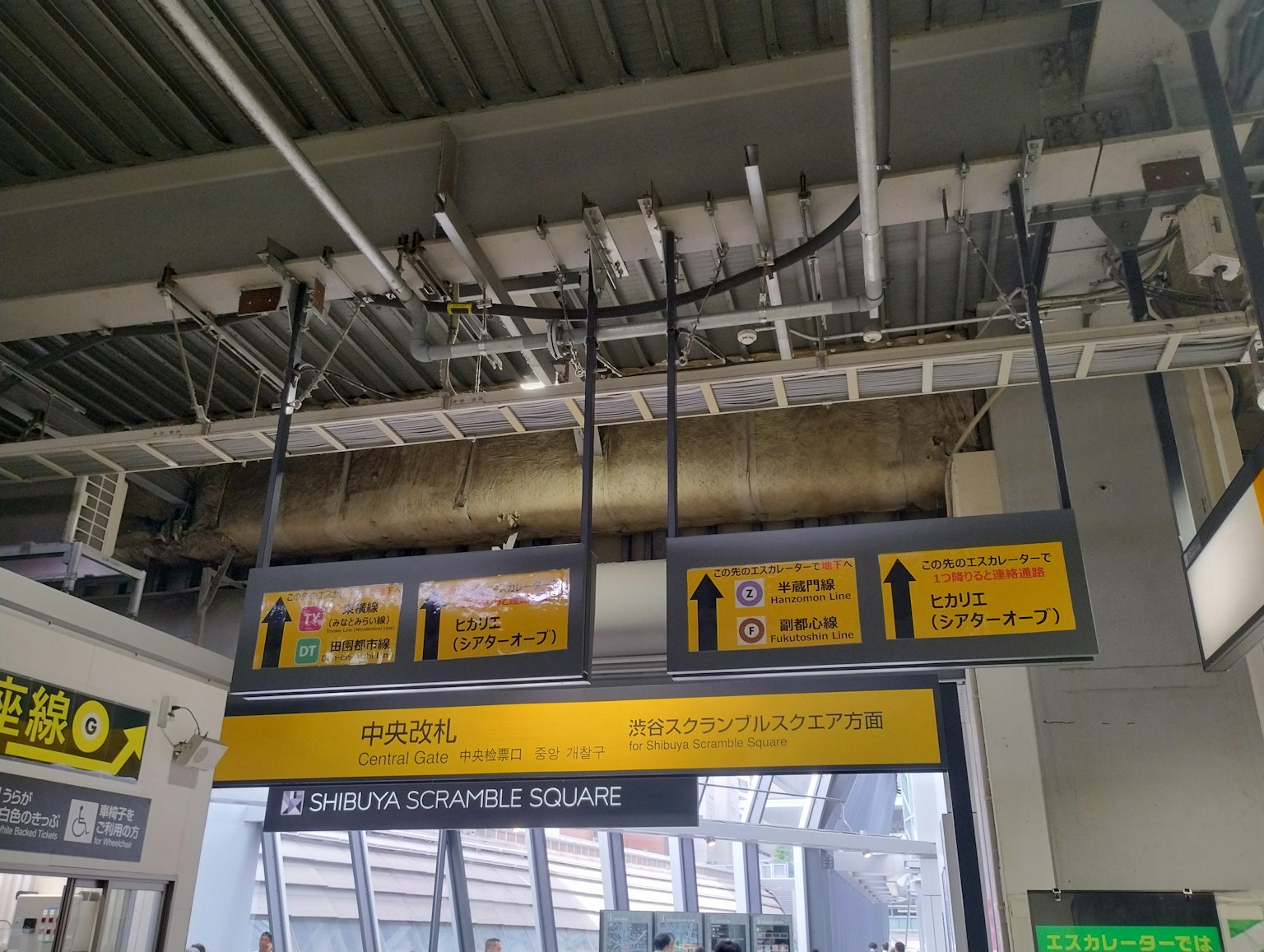 Gambar menunjukkan tanda arah dan struktur langit-langit di Stasiun Shinjuku