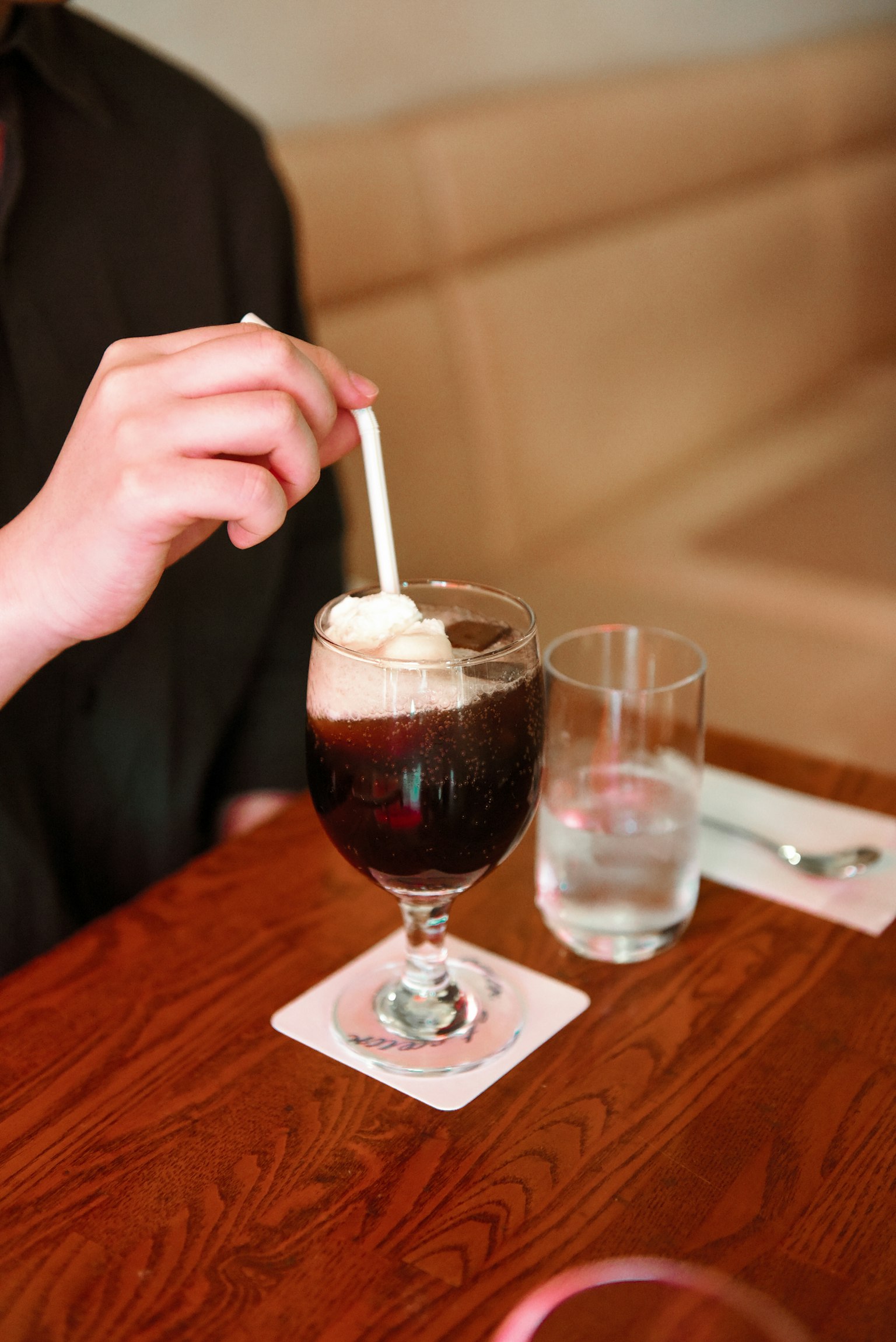 手正在攪拌一杯加了奶油的冰咖啡飲料