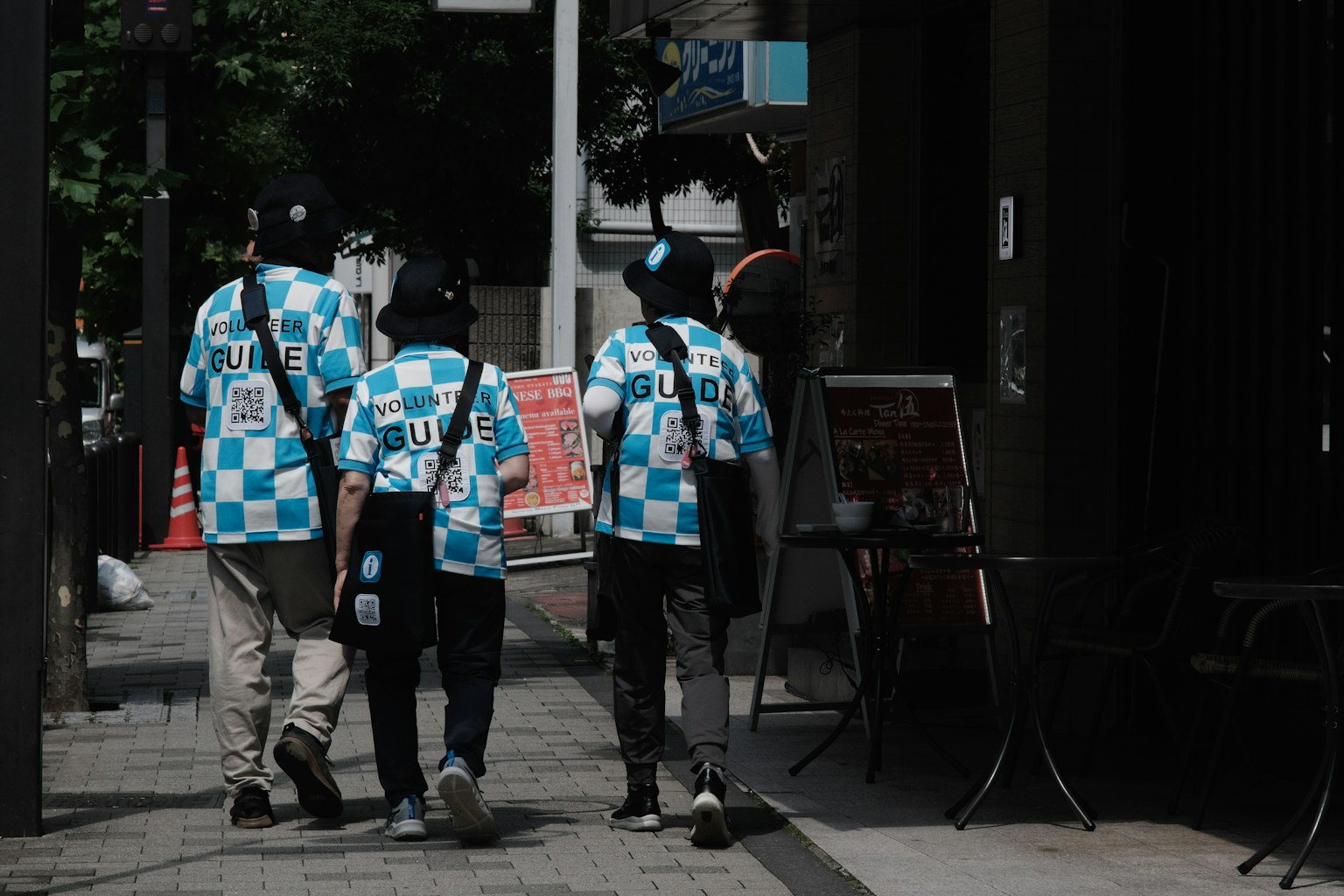 Un gruppo di quattro persone che indossano camicie a scacchi blu e bianche mentre camminano per la strada