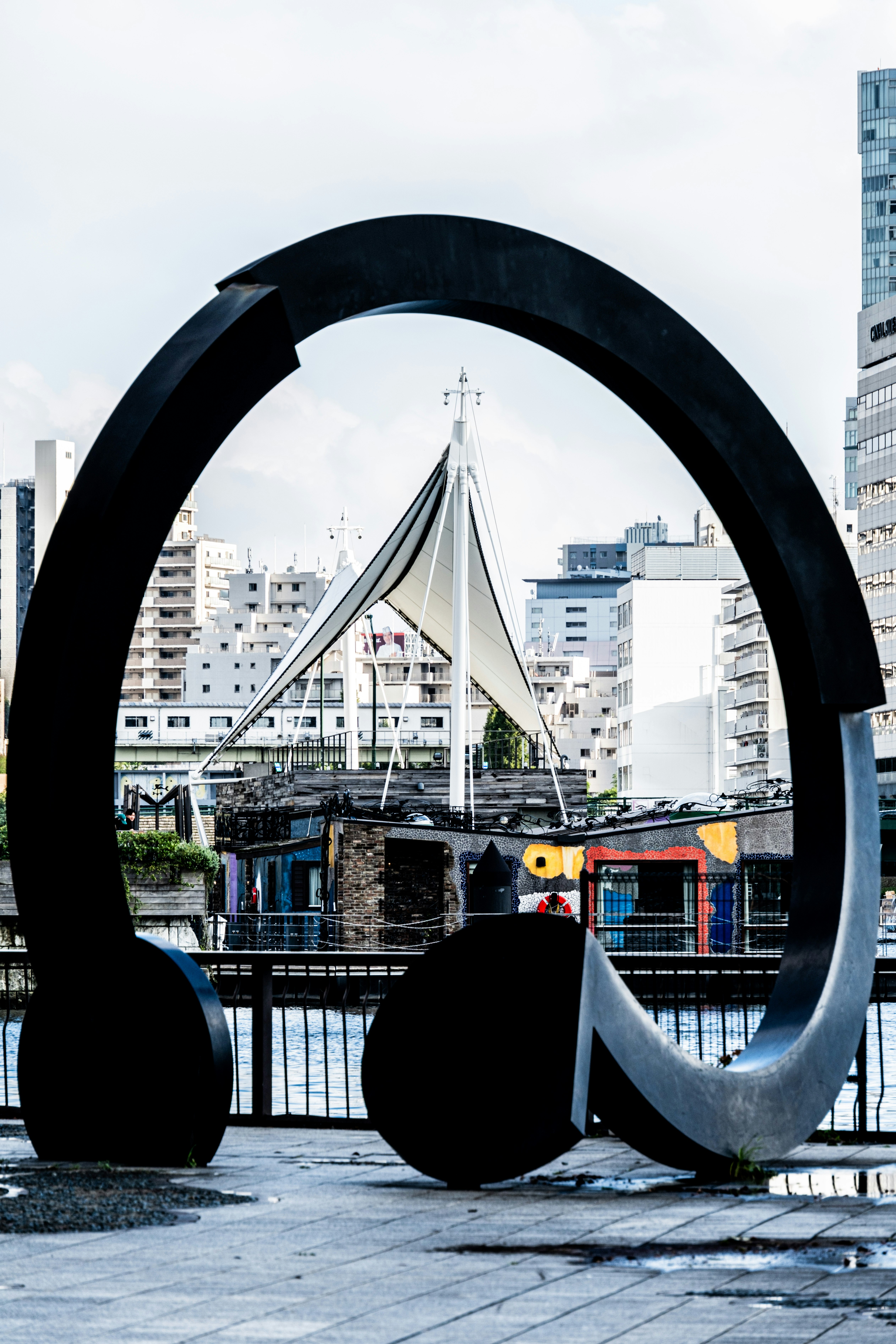 Außenplatz mit großem schwarzem Metallmonument und umliegenden Stadtgebäuden