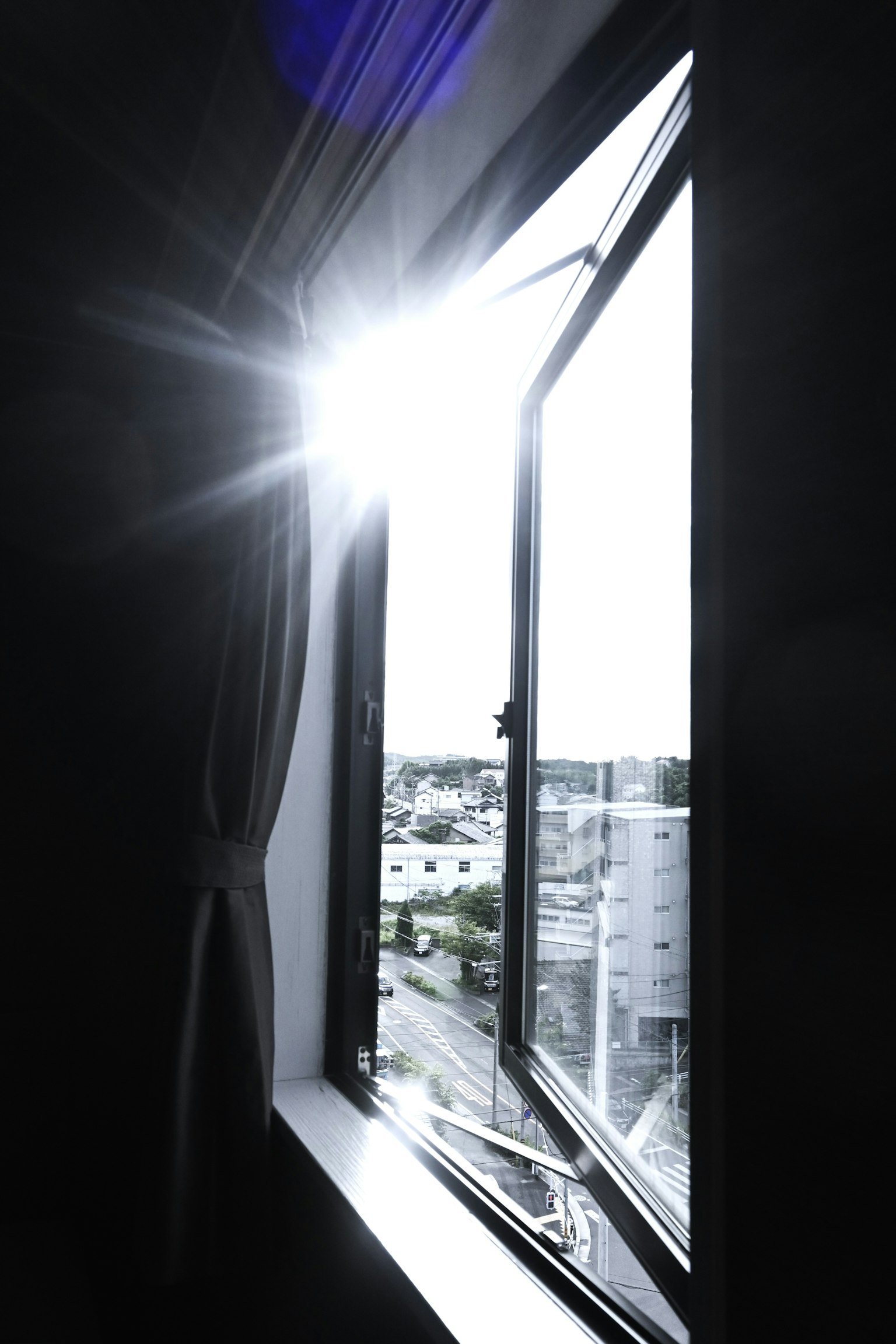 Un coin d'une pièce avec la lumière du soleil entrant par une fenêtre ouverte montrant la vue extérieure