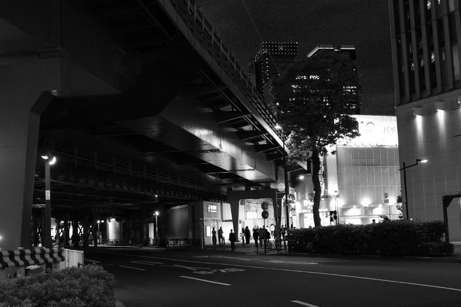 Scène urbaine nocturne avec une route surélevée et des silhouettes de personnes