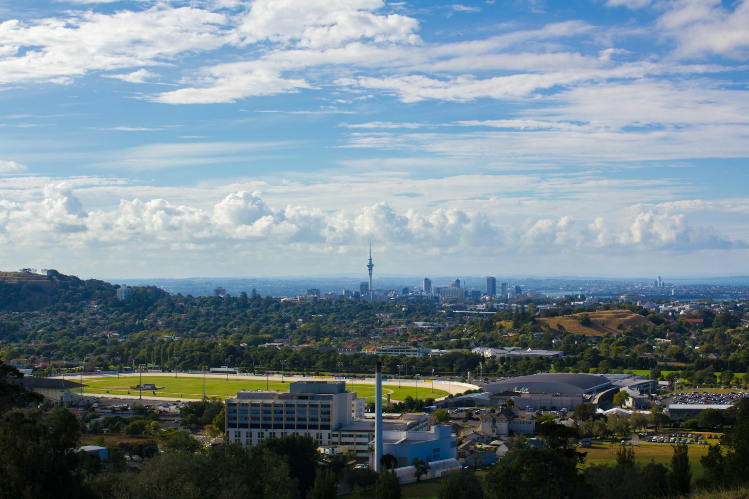 Vue scénique avec un ciel vibrant et des nuages, skyline de la ville entourée de collines verdoyantes