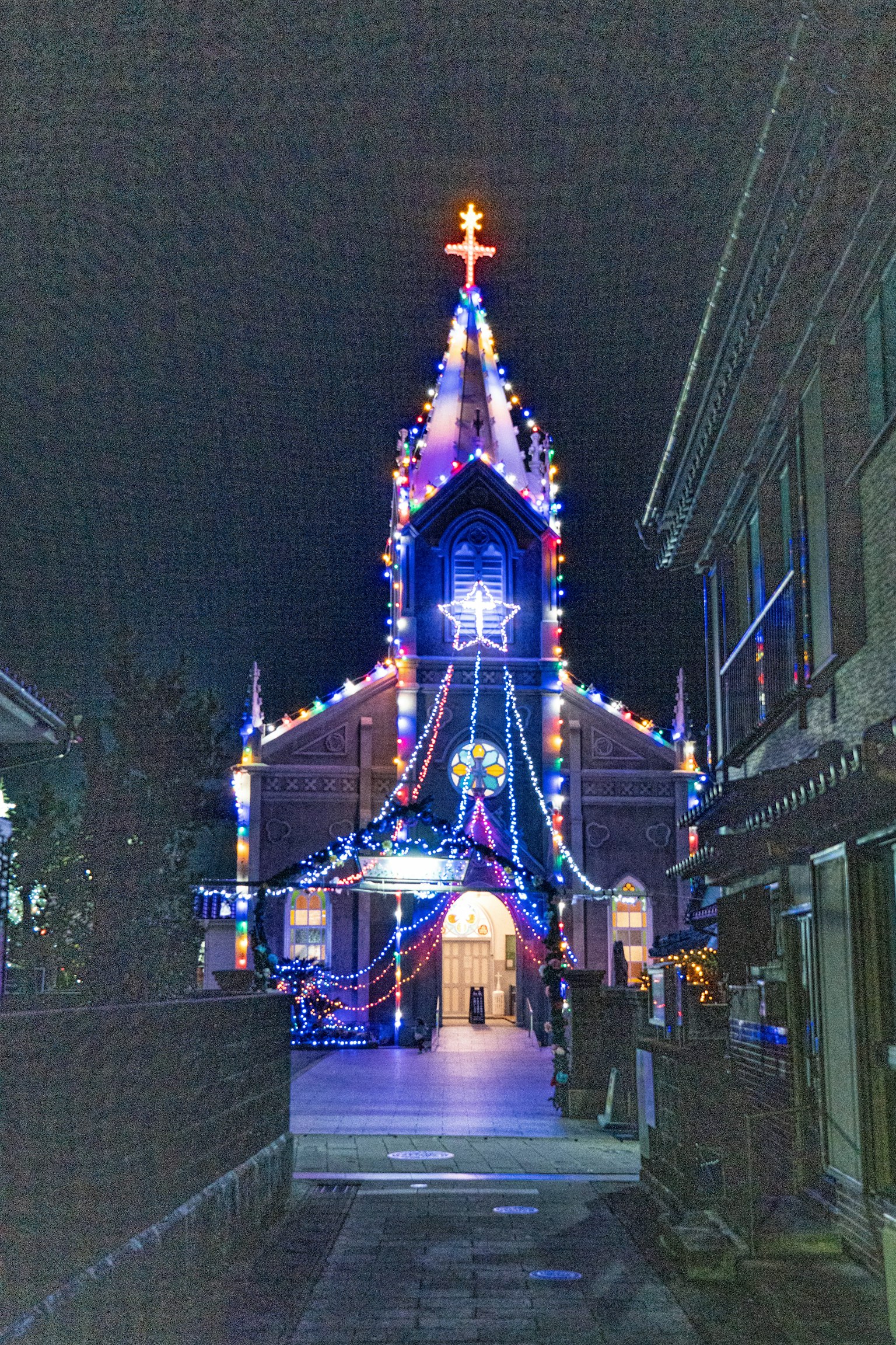 Fachada de la iglesia adornada con luces coloridas de noche
