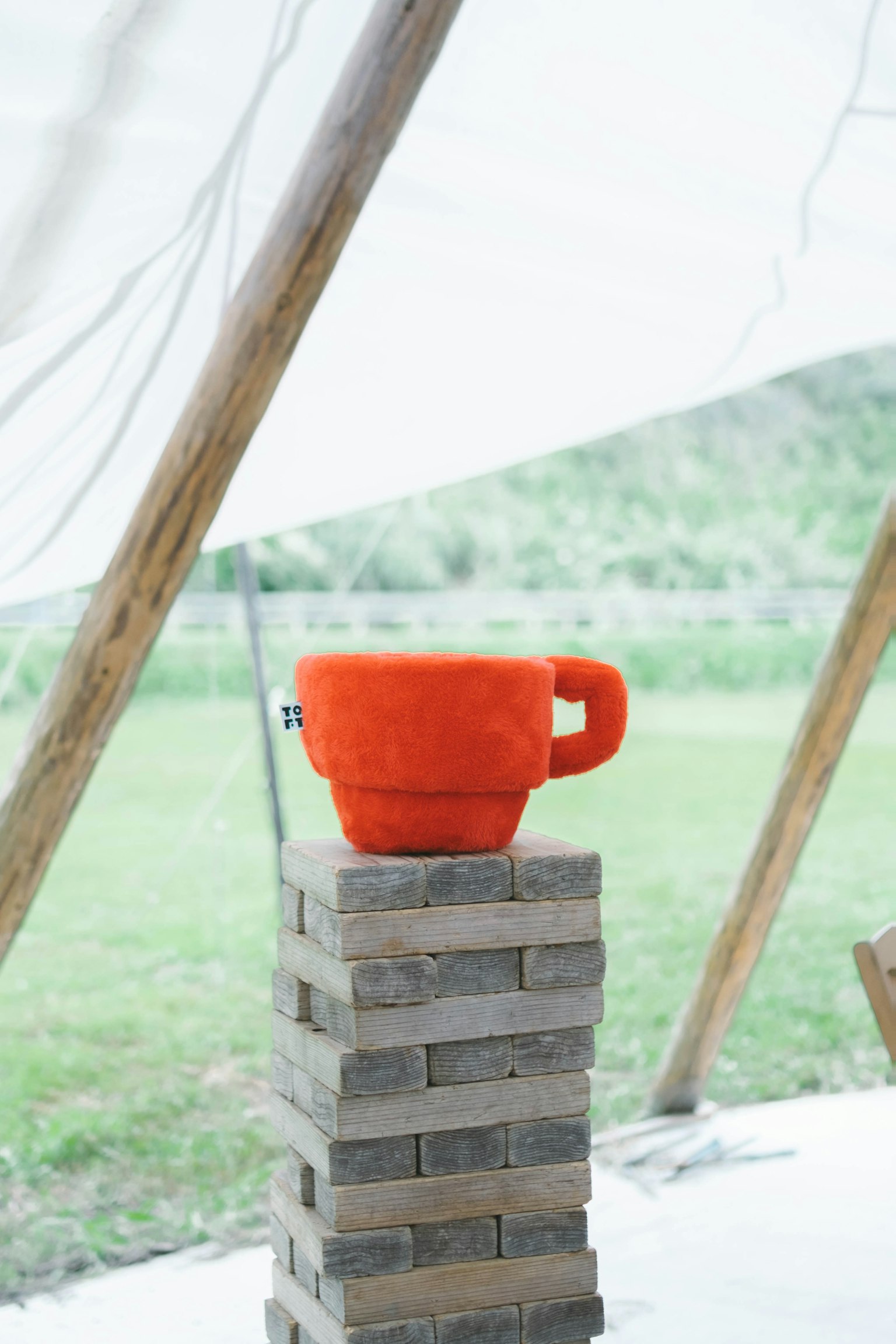 Eine orangefarbene Tasse auf einem Stapel Holzblöcke in einer Außenszene
