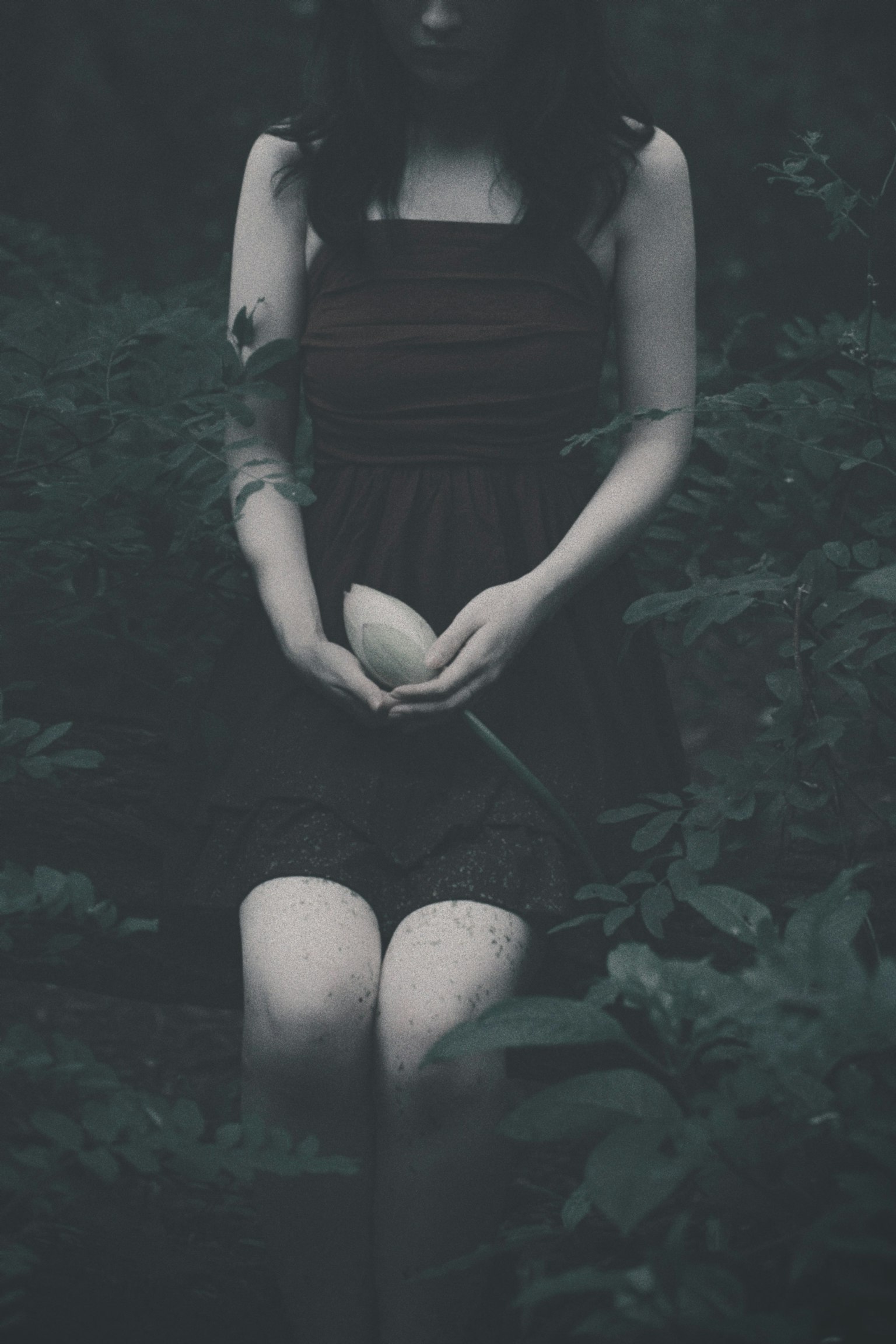 Una chica sosteniendo un huevo blanco en un bosque oscuro