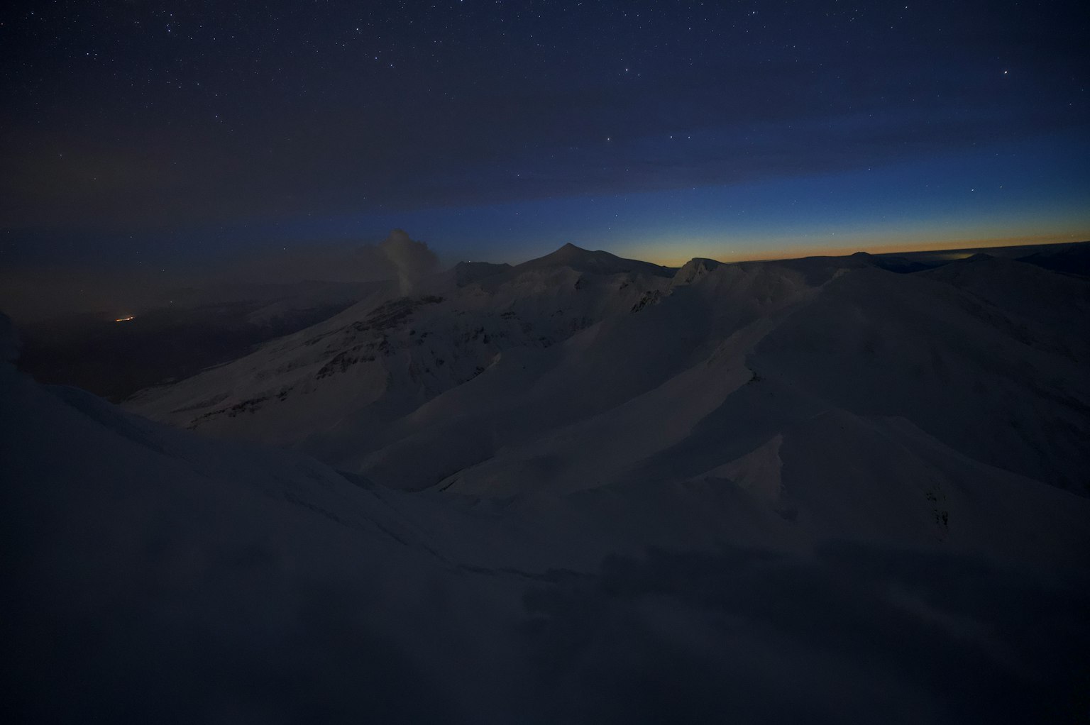 Silhouette di montagne sotto un cielo notturno con stelle