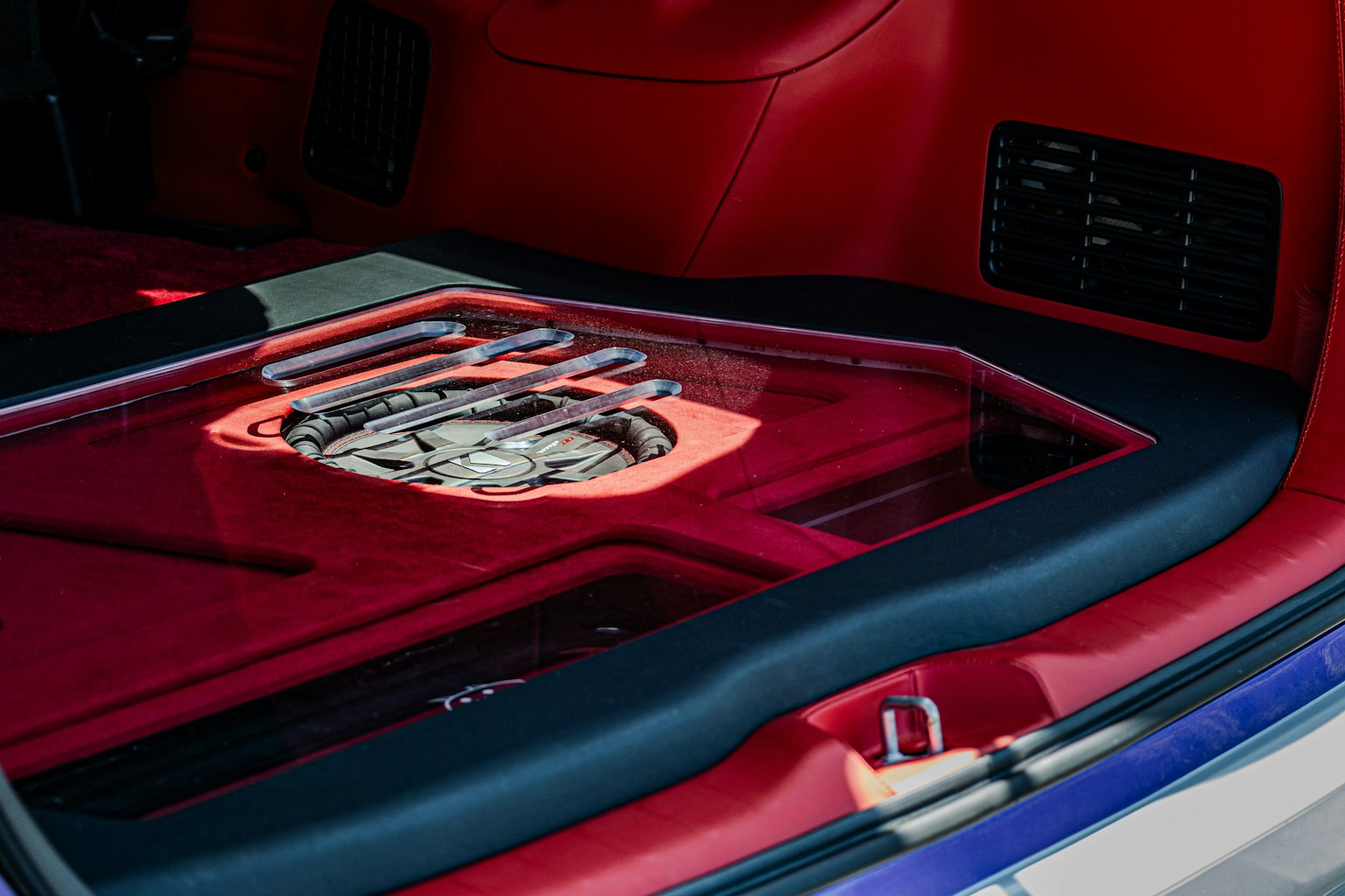 Transparent subwoofer mounted in a red car trunk with custom design panel
