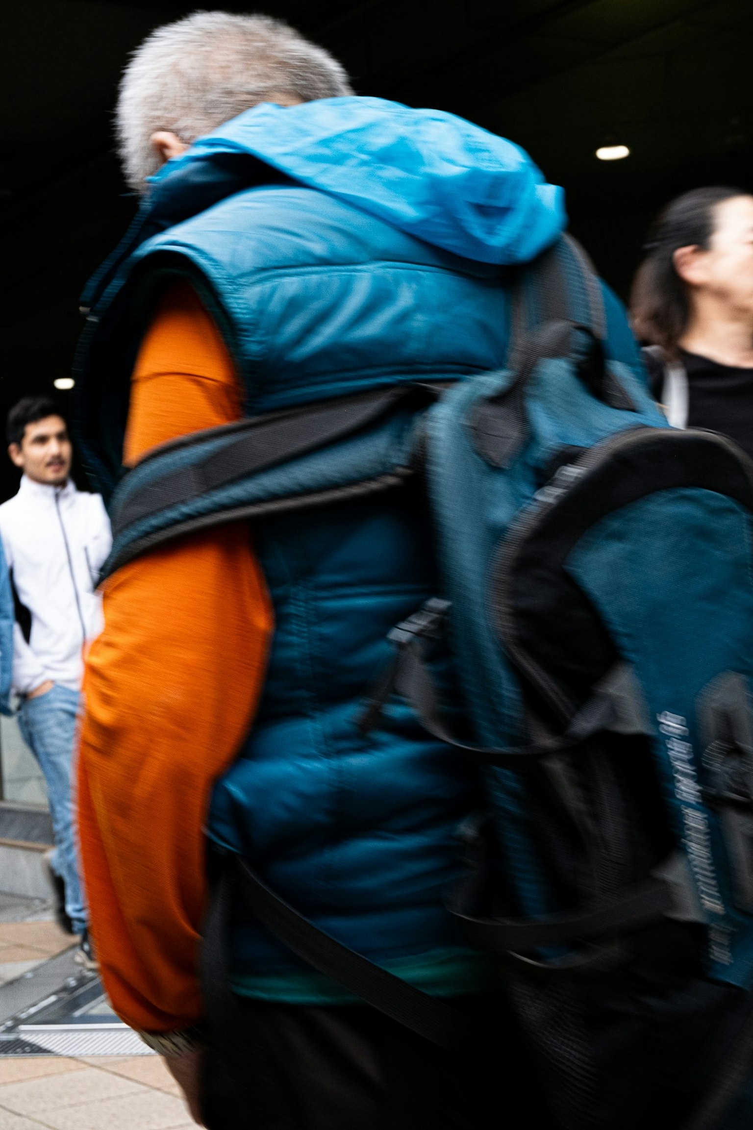 Un homme portant une veste en duvet bleue marchant avec un sac à dos
