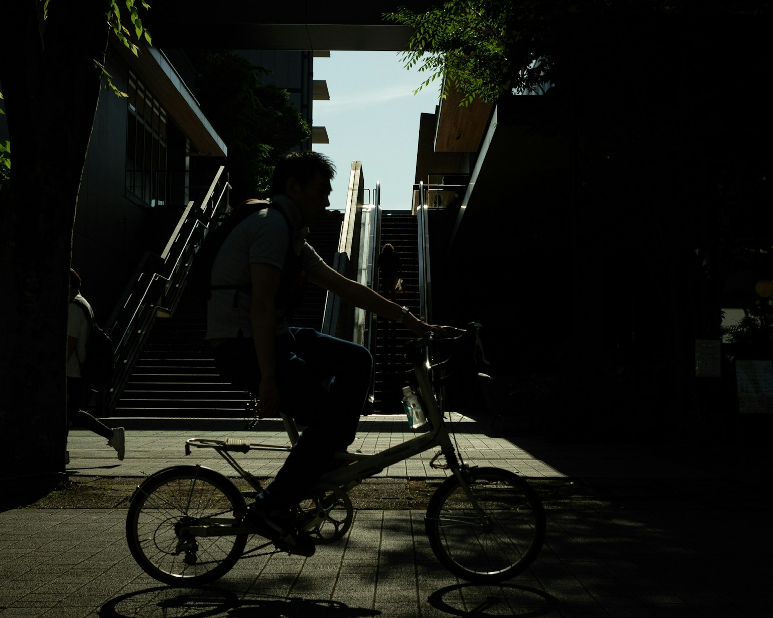 Silhouette einer Person auf einem Fahrrad mit Treppe im Hintergrund