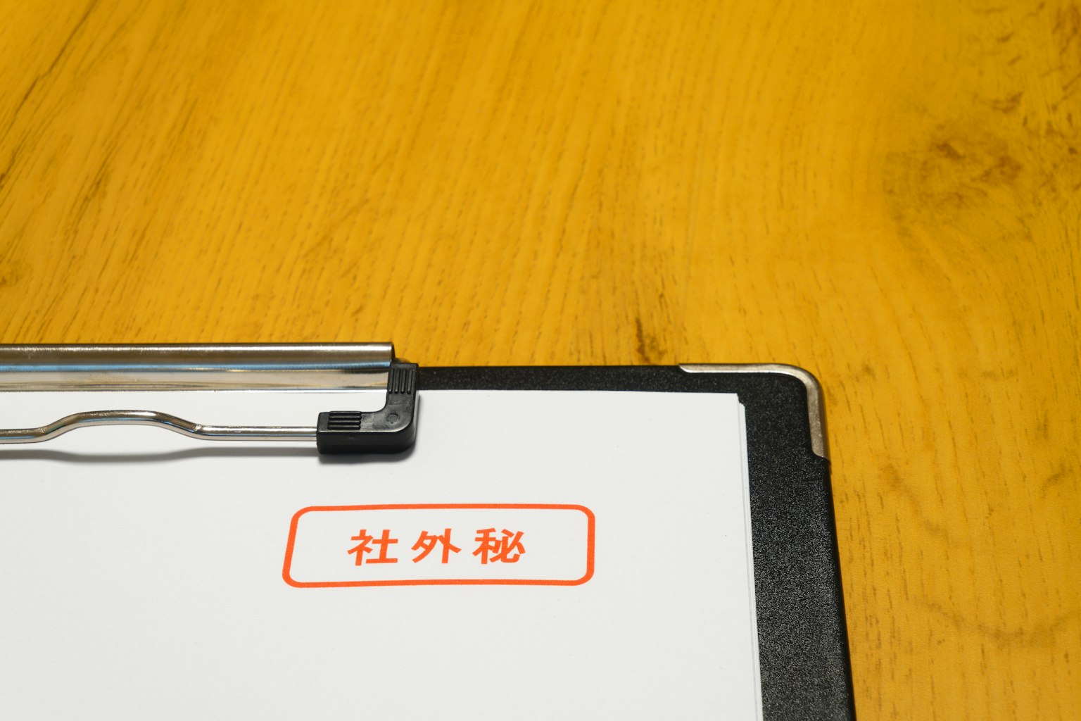 木桌上的夾子和白紙，上面有紅色文字標記為機密