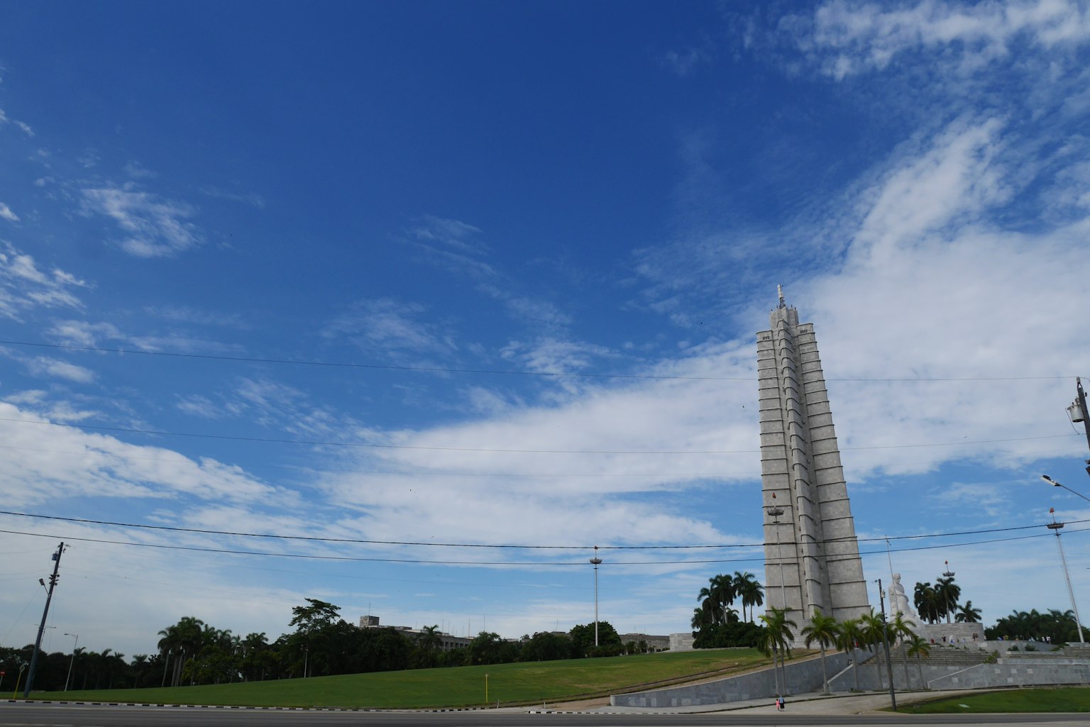 Hoher Turm unter blauem Himmel mit grünem Gras und Wolken