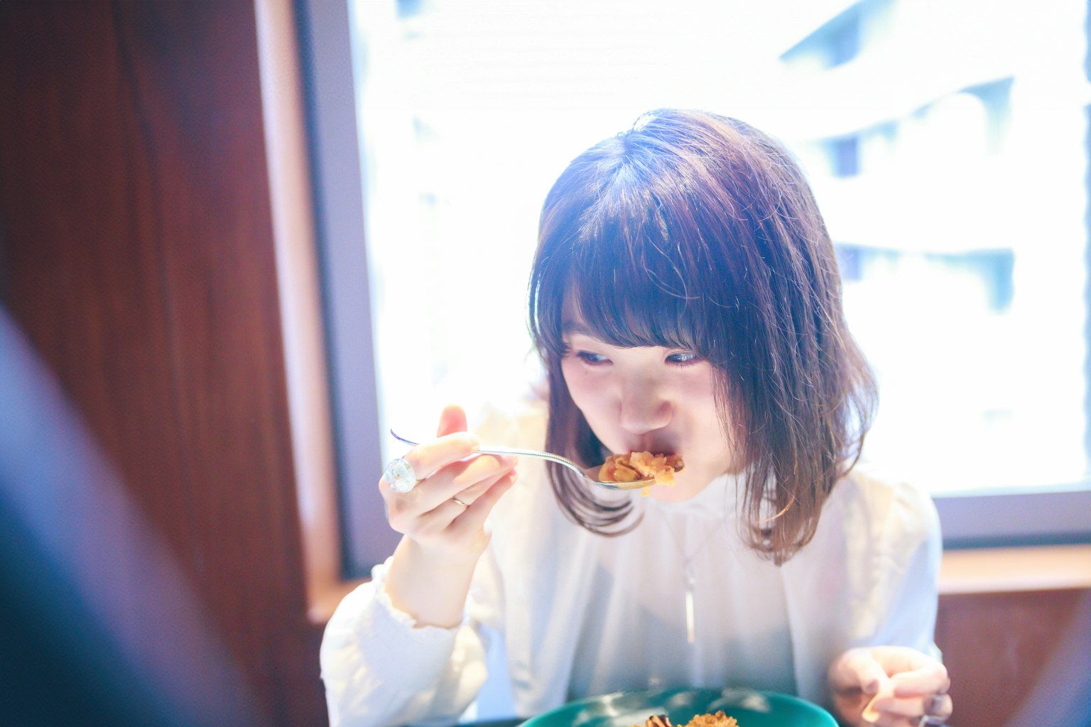 A woman enjoying a meal in a cafe with bright light coming through the window