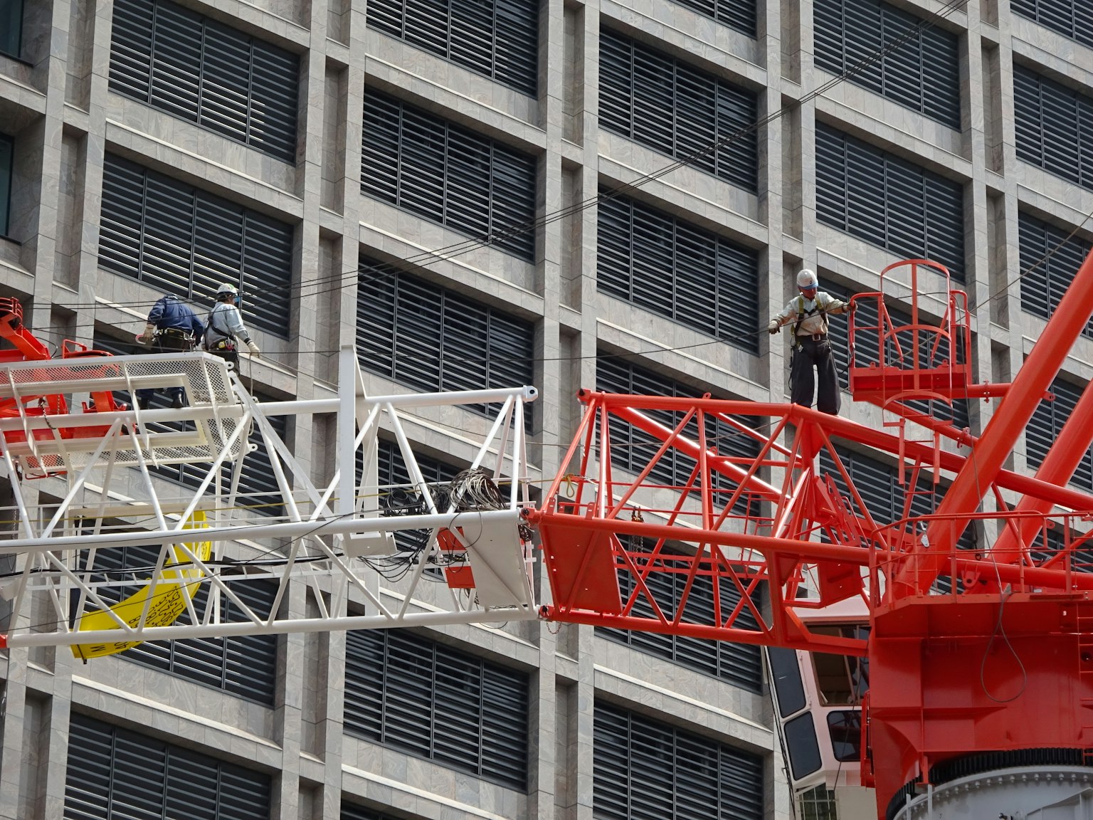 Construction workers on a red crane at a building site