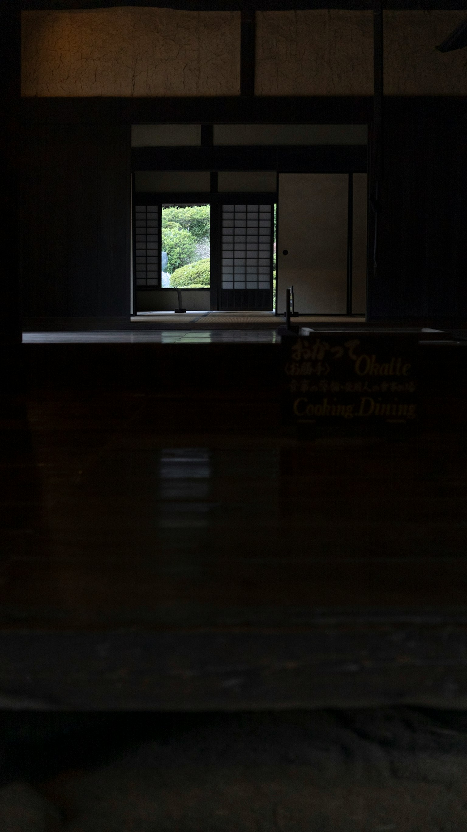 Chambre sombre avec une fenêtre révélant un paysage vert