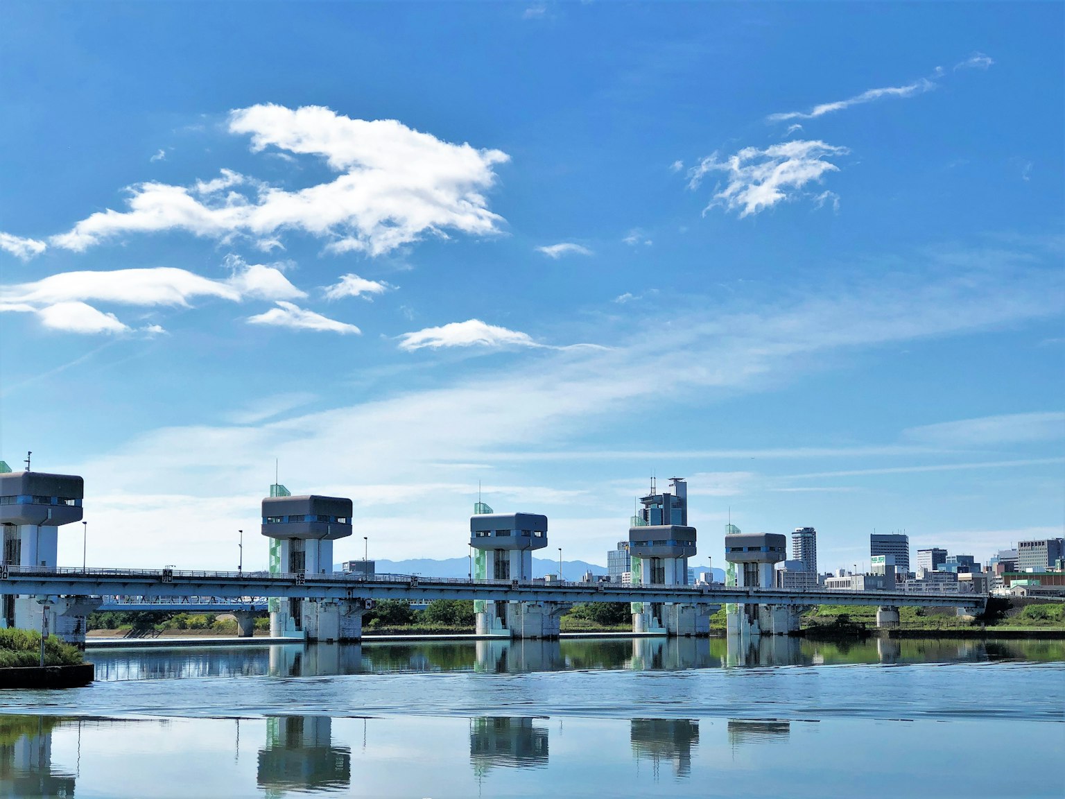 Foto di un fiume con chiuse e skyline urbano sotto un cielo blu