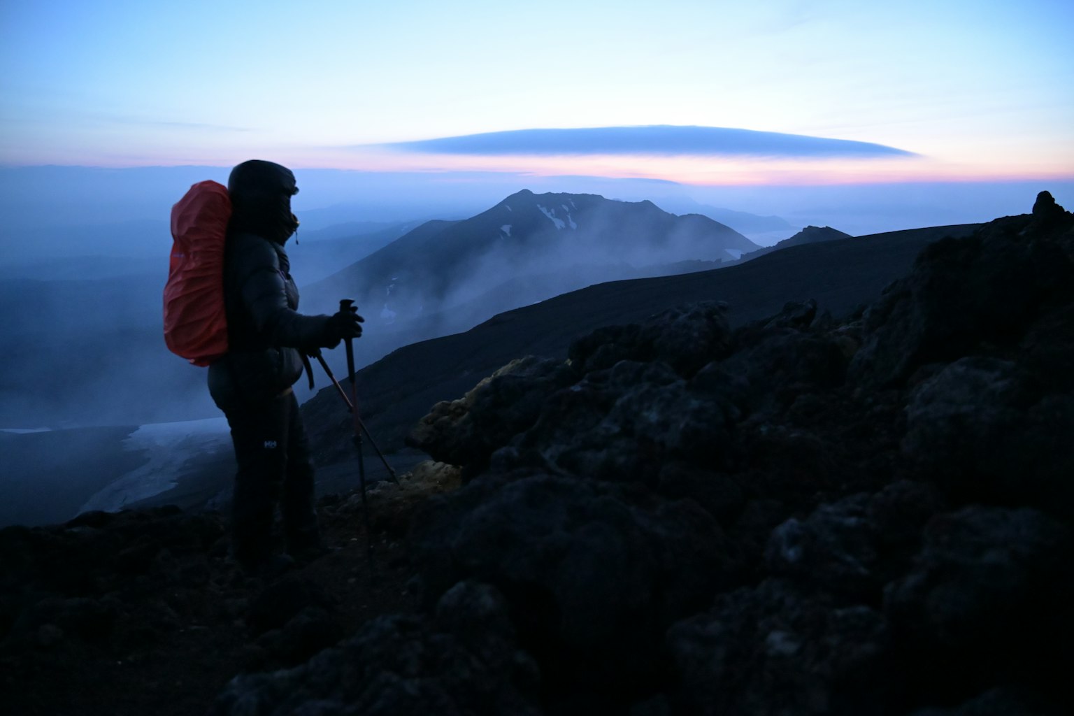 Hiker standing on a mountain summit with a twilight sky