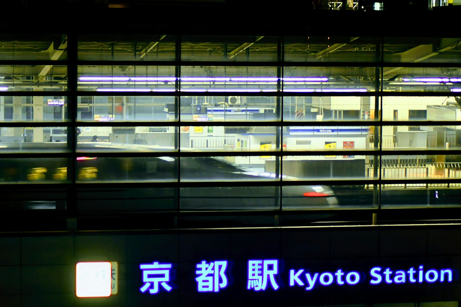 Insegna della stazione di Kyoto con un treno in transito di notte