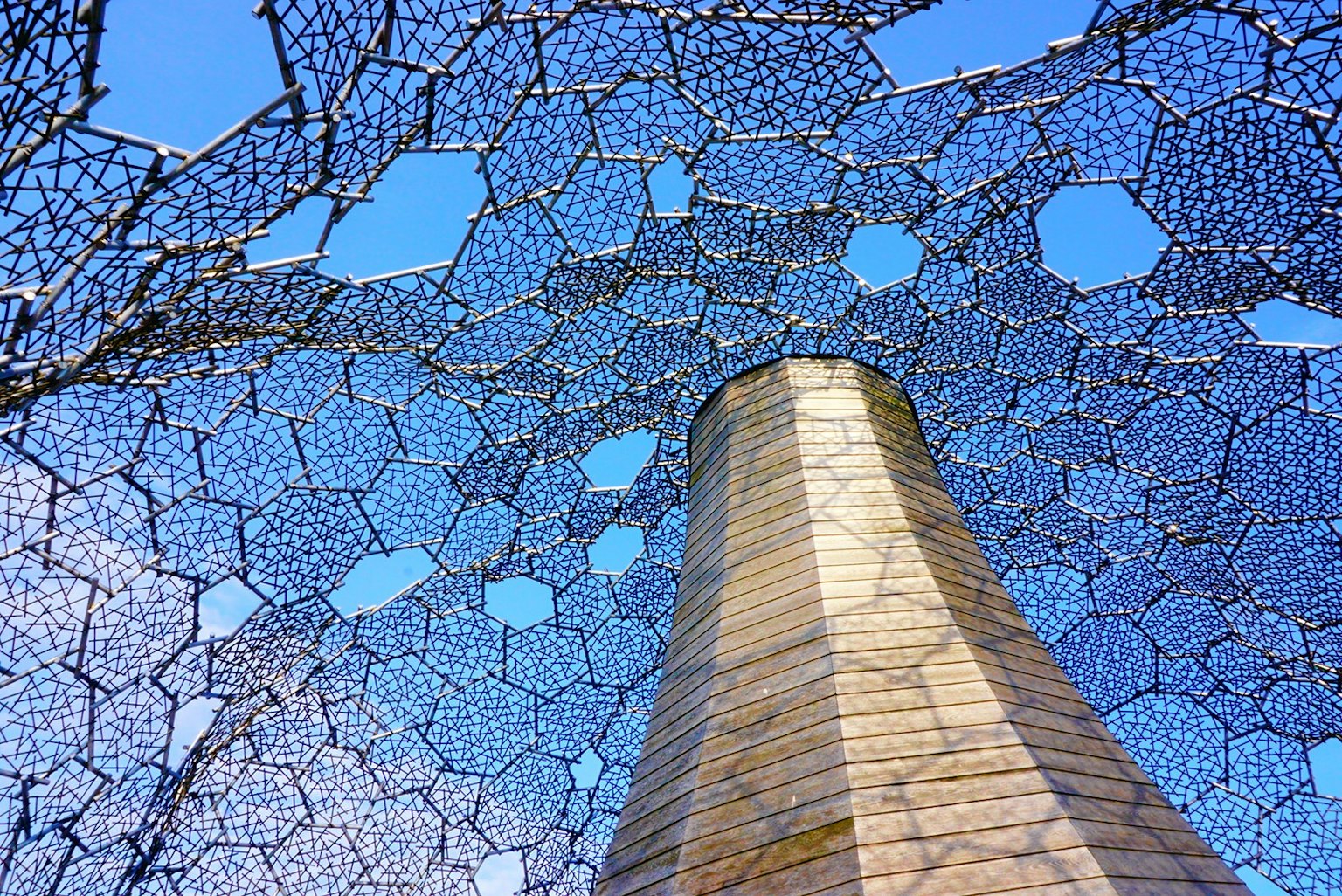 Vue d'une cheminée recouverte d'une structure en filet hexagonal avec ciel bleu