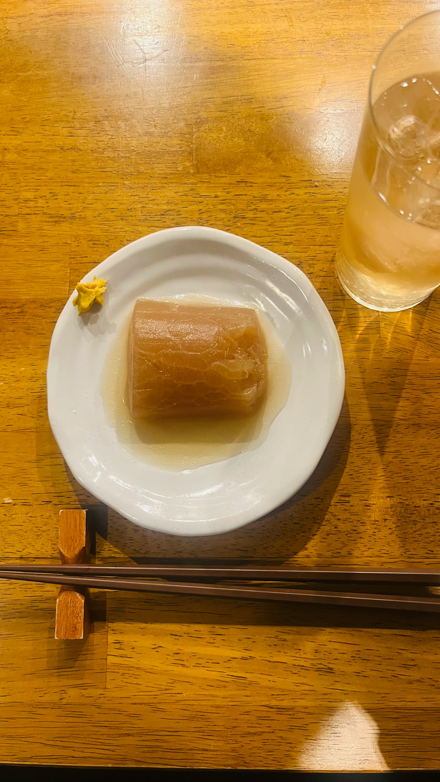 A plate with a translucent jelly dessert and chopsticks beside a drink
