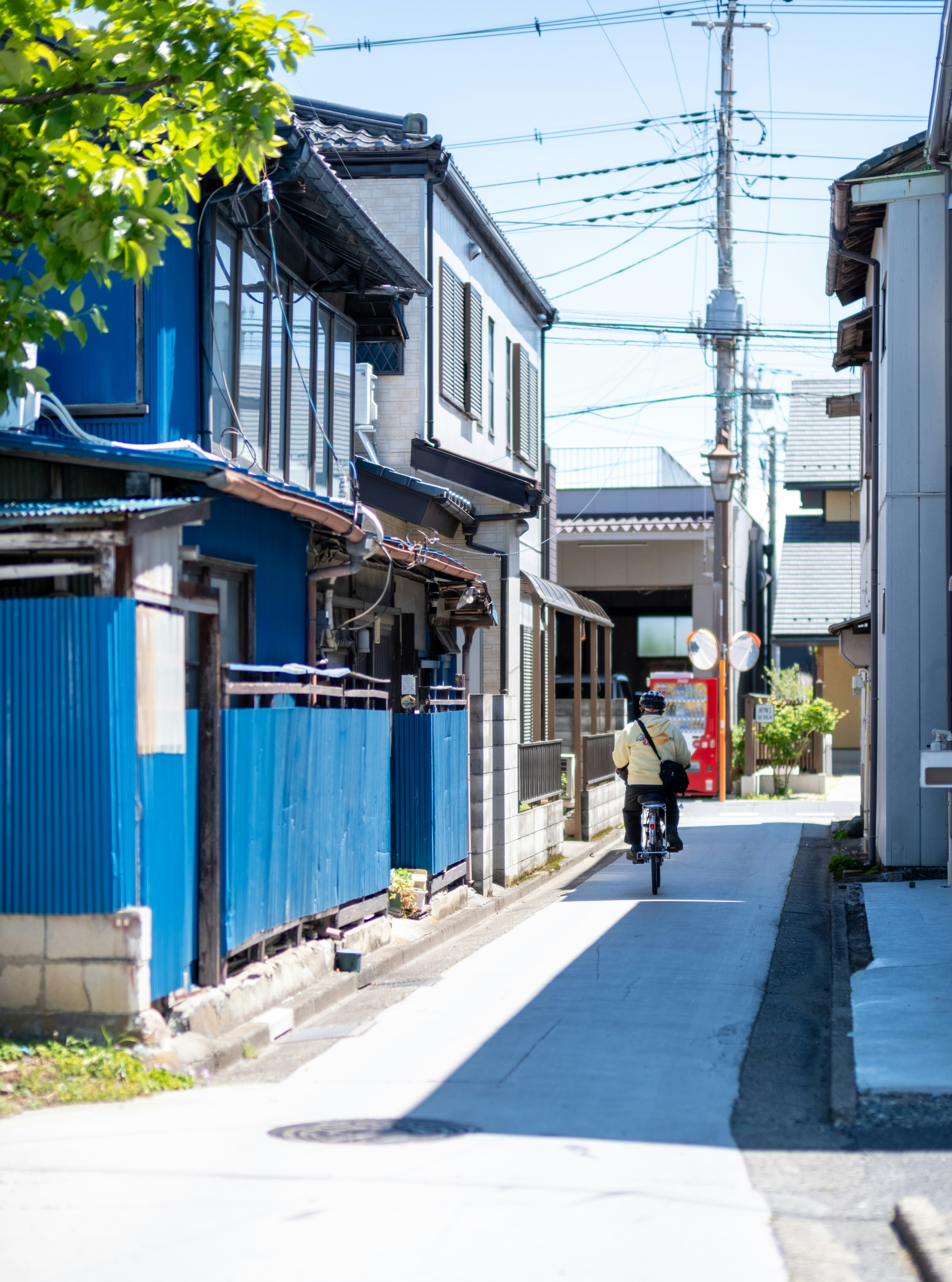 路地に並ぶ青い塀と自転車のある住宅街