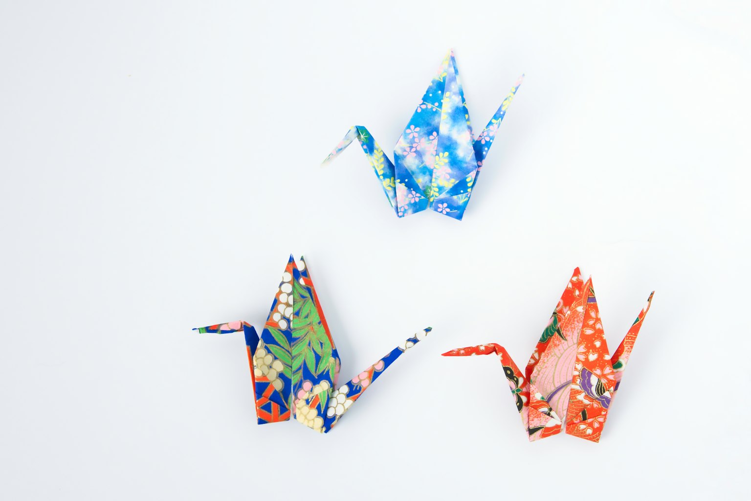 Grúas de origami coloridas exhibidas sobre un fondo blanco