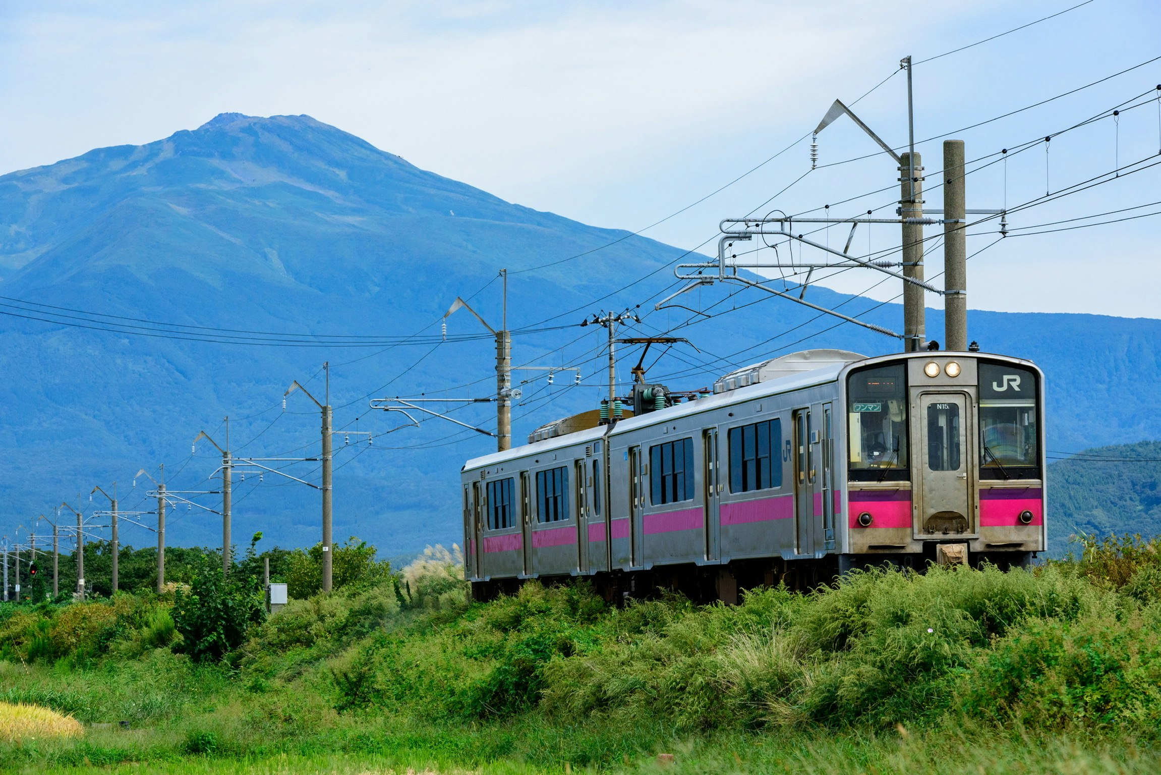 鳥海山を背景に走る二両編成のローカル線の電車の風景