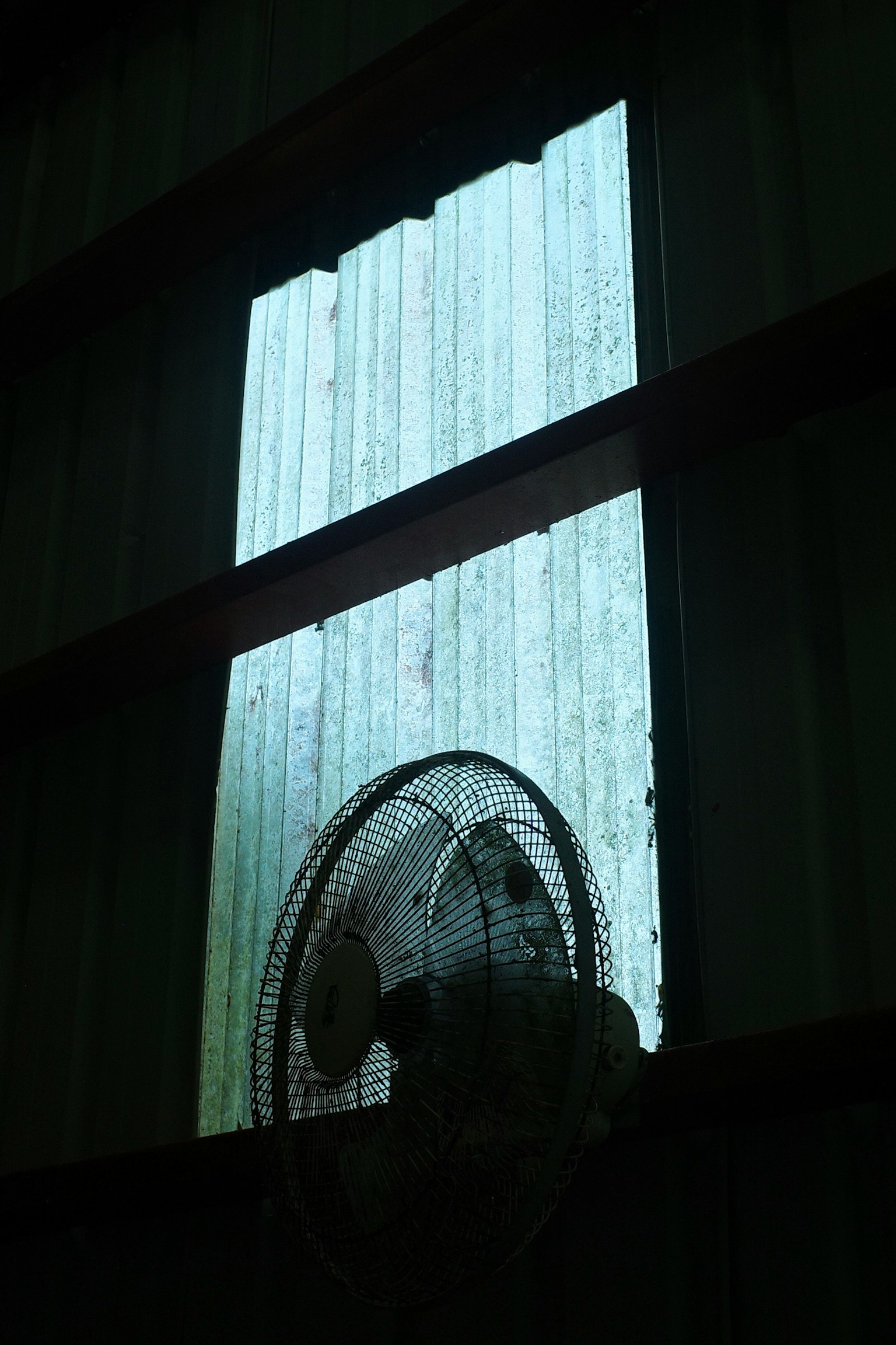 昏暗房间内的窗户和风扇的图像 蓝光透过窗户照射进来