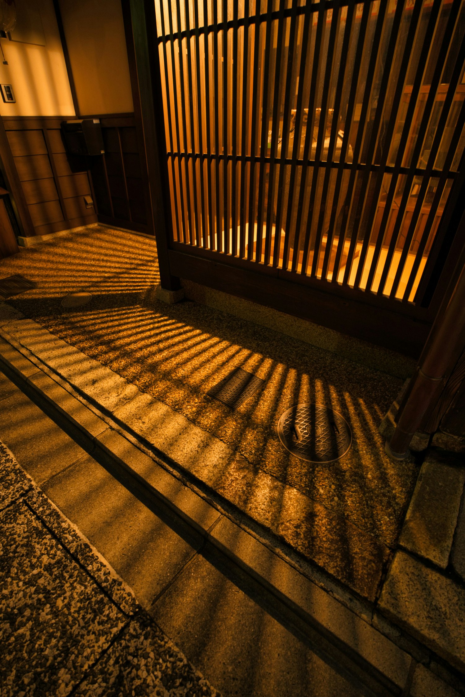 京都・上七軒の京町家の格子と灯りが映る路地の夜景