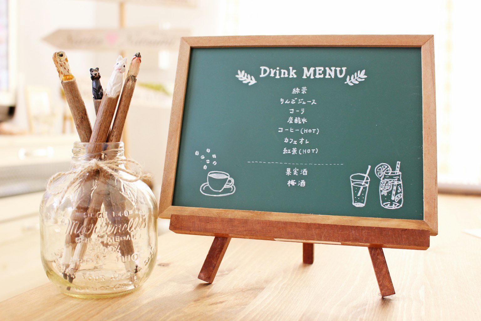 A chalkboard drink menu displayed on an easel with a jar of pens