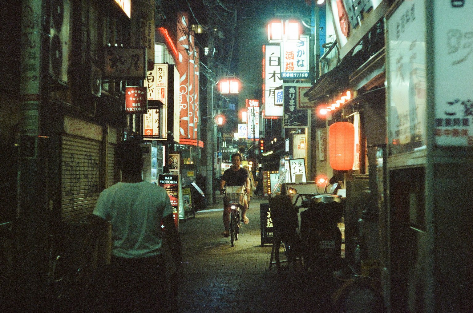 一個人在夜間街道上走，周圍有明亮的霓虹燈