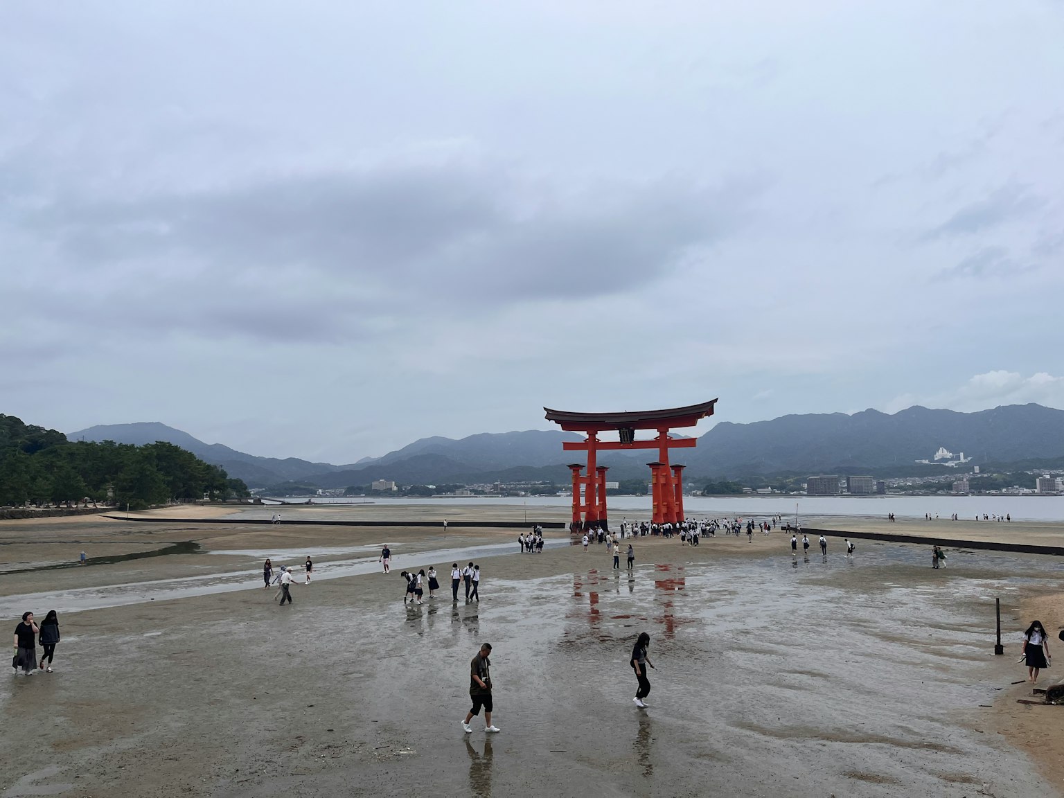 Vue du torii du sanctuaire d'Itsukushima et des personnes marchant sur le rivage découvert