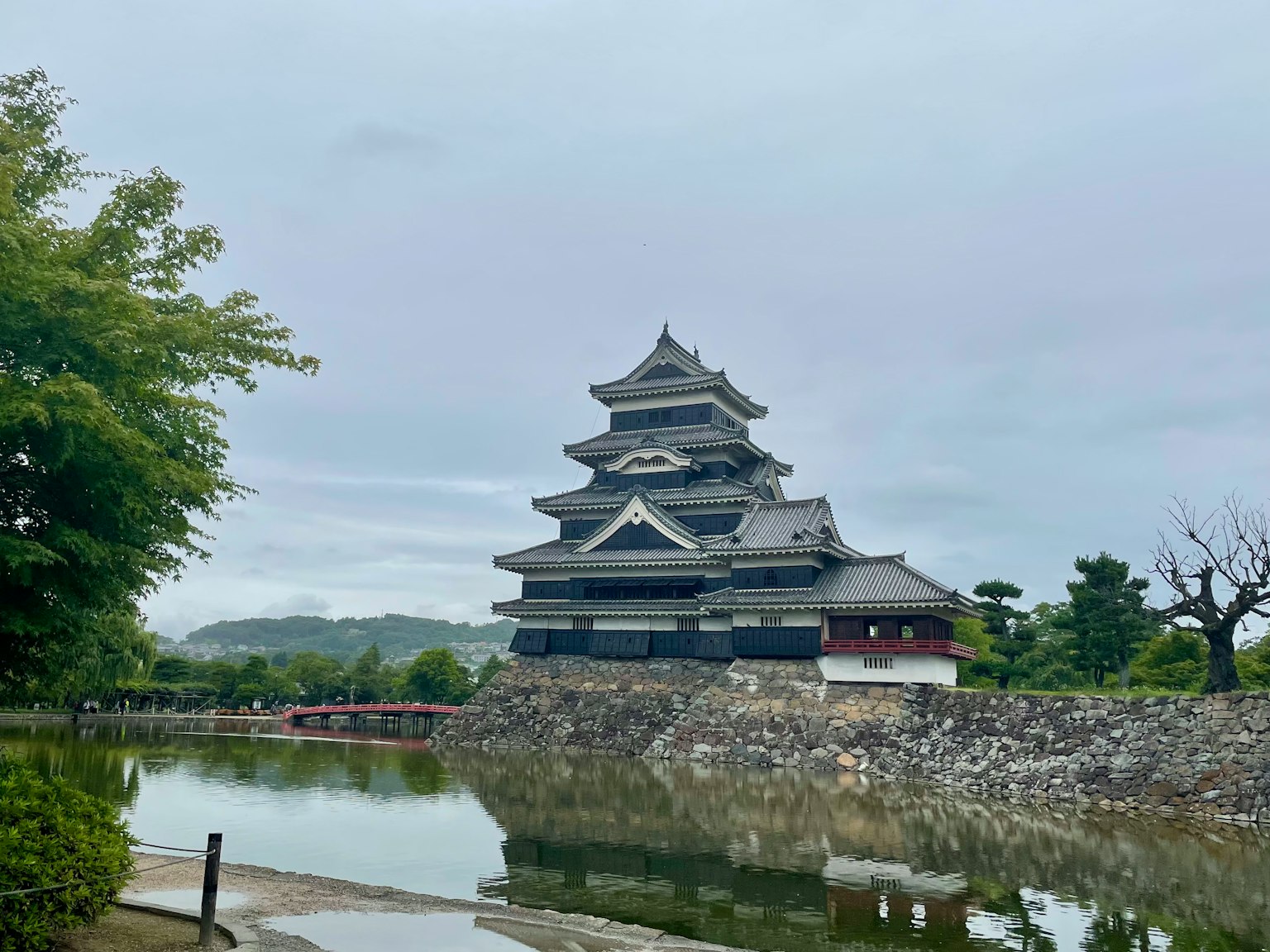 View of Matsumoto Castle with a black structure reflecting in the adjacent pond