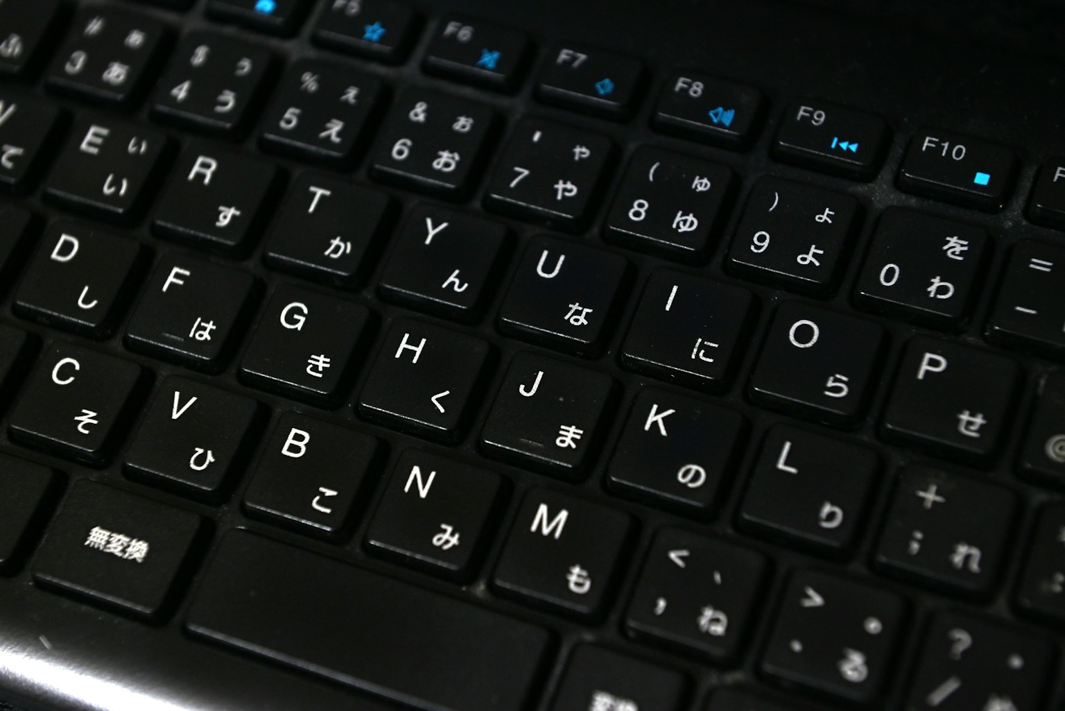 Nahaufnahme einer schwarzen Tastatur mit einer Mischung aus japanischen und englischen Zeichen