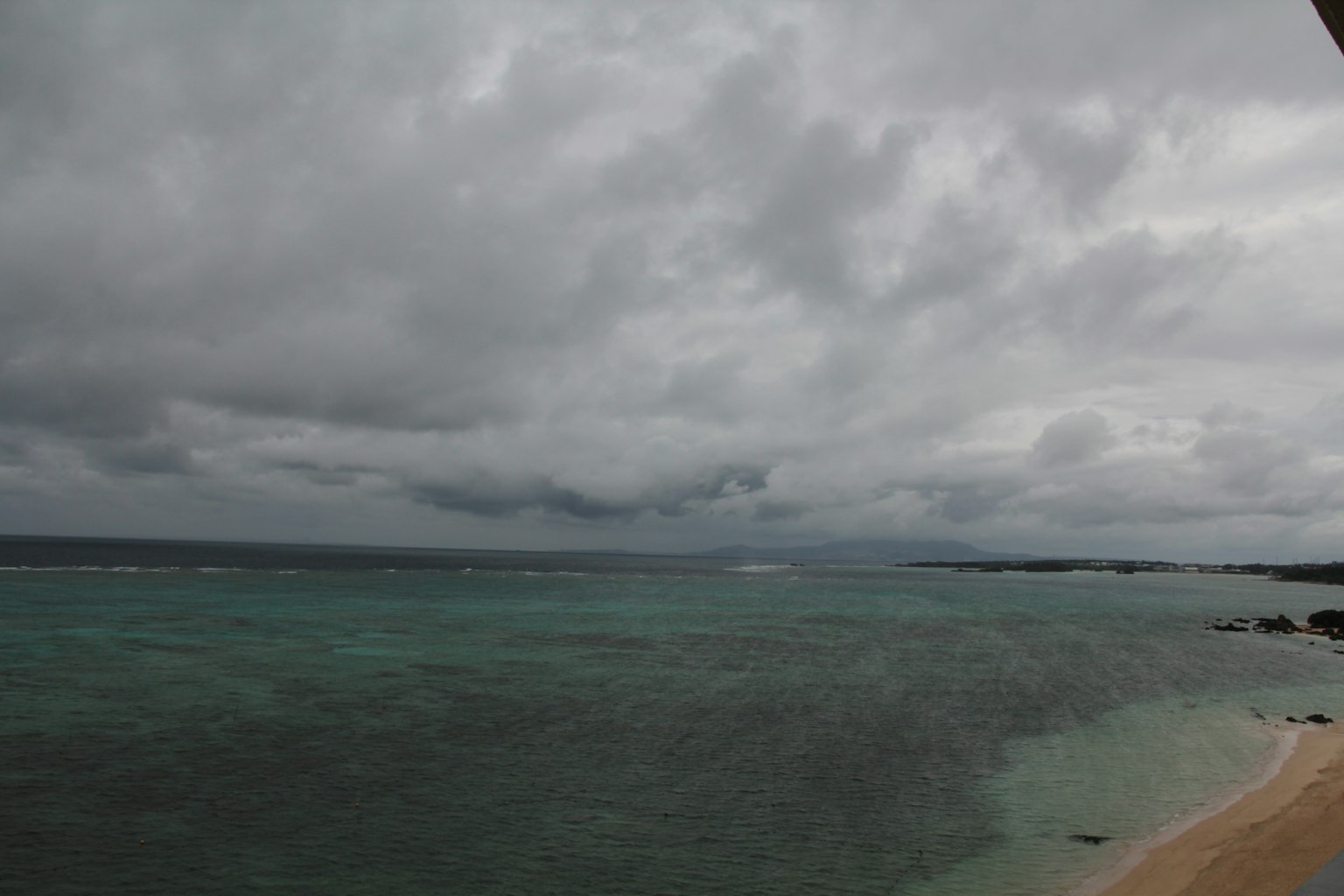 วิวทะเลสีเขียวมรกตและชายหาดภายใต้ท้องฟ้าที่มีเมฆมาก